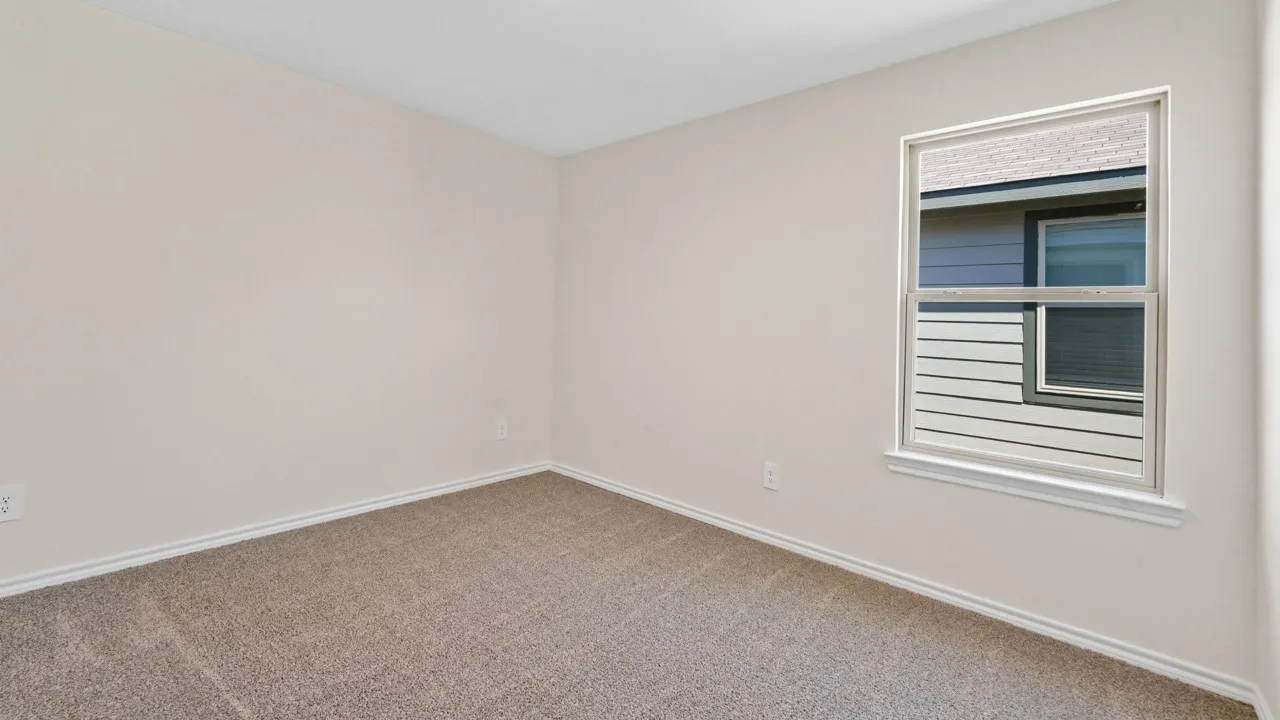 Neutral-toned wall paint, carpeted flooring, and a double-hung window with white trim