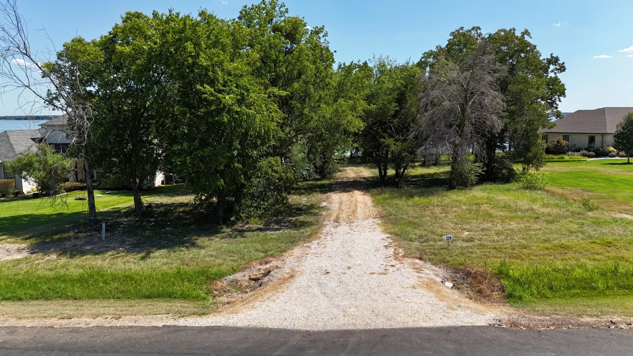 Gravel drive leads through mature trees toward the waterfront of this Richland Chambers Lake property in Navarro County.
