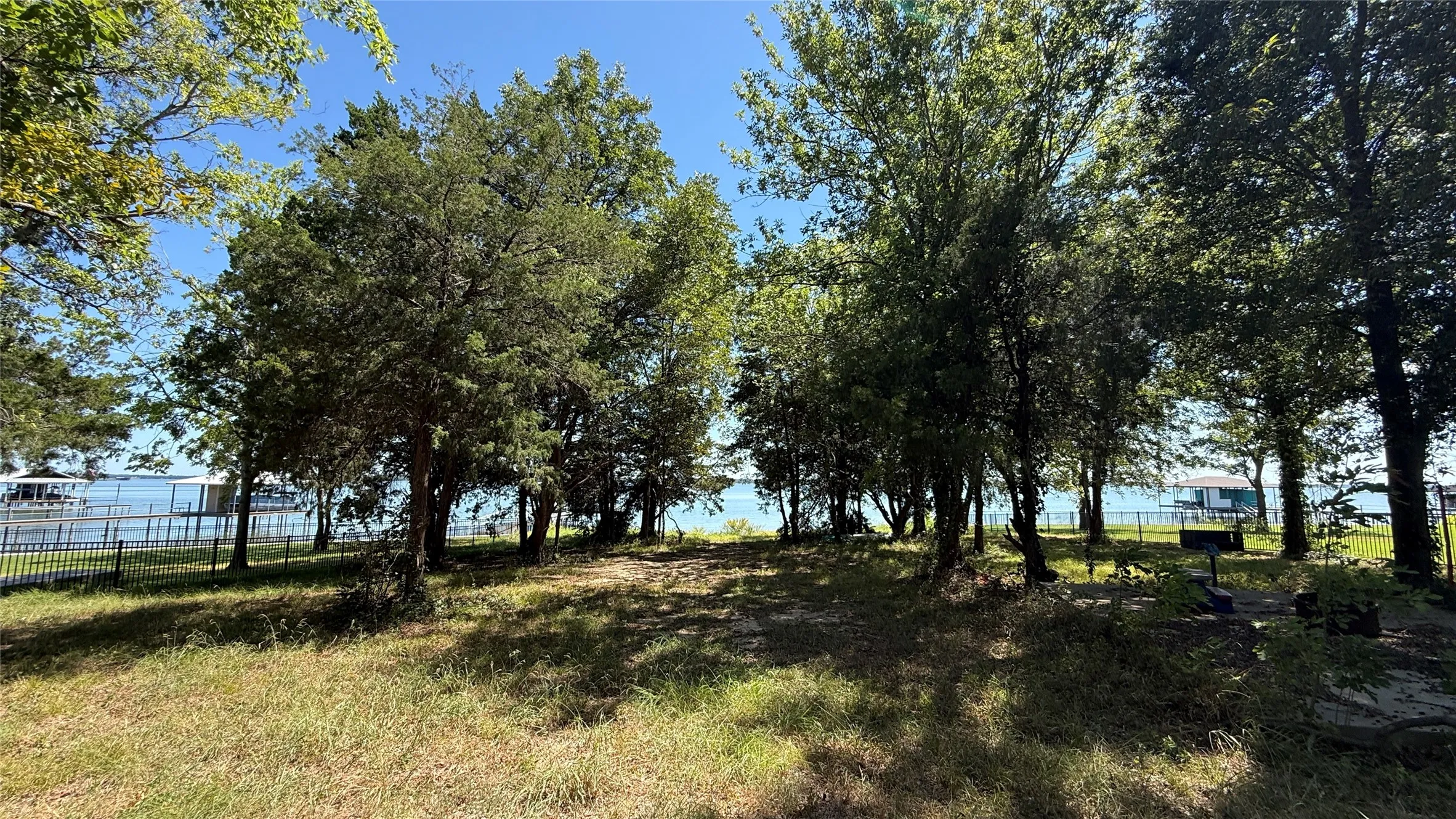 Towering trees provide natural shade across a peaceful Central Texas building site with beautiful views toward the lake.