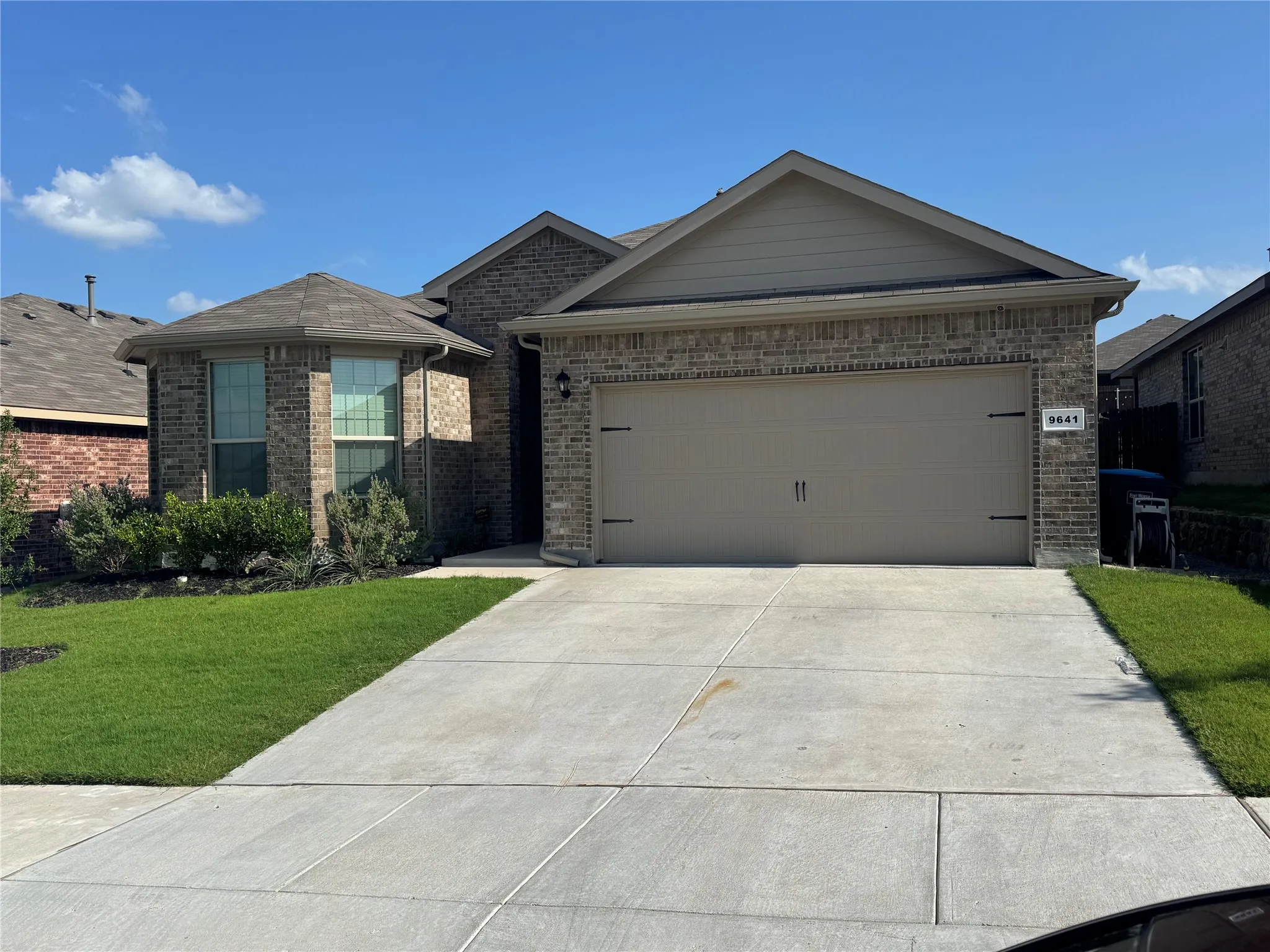 Ranch-style home featuring brick siding, a front lawn, driveway, and a garage