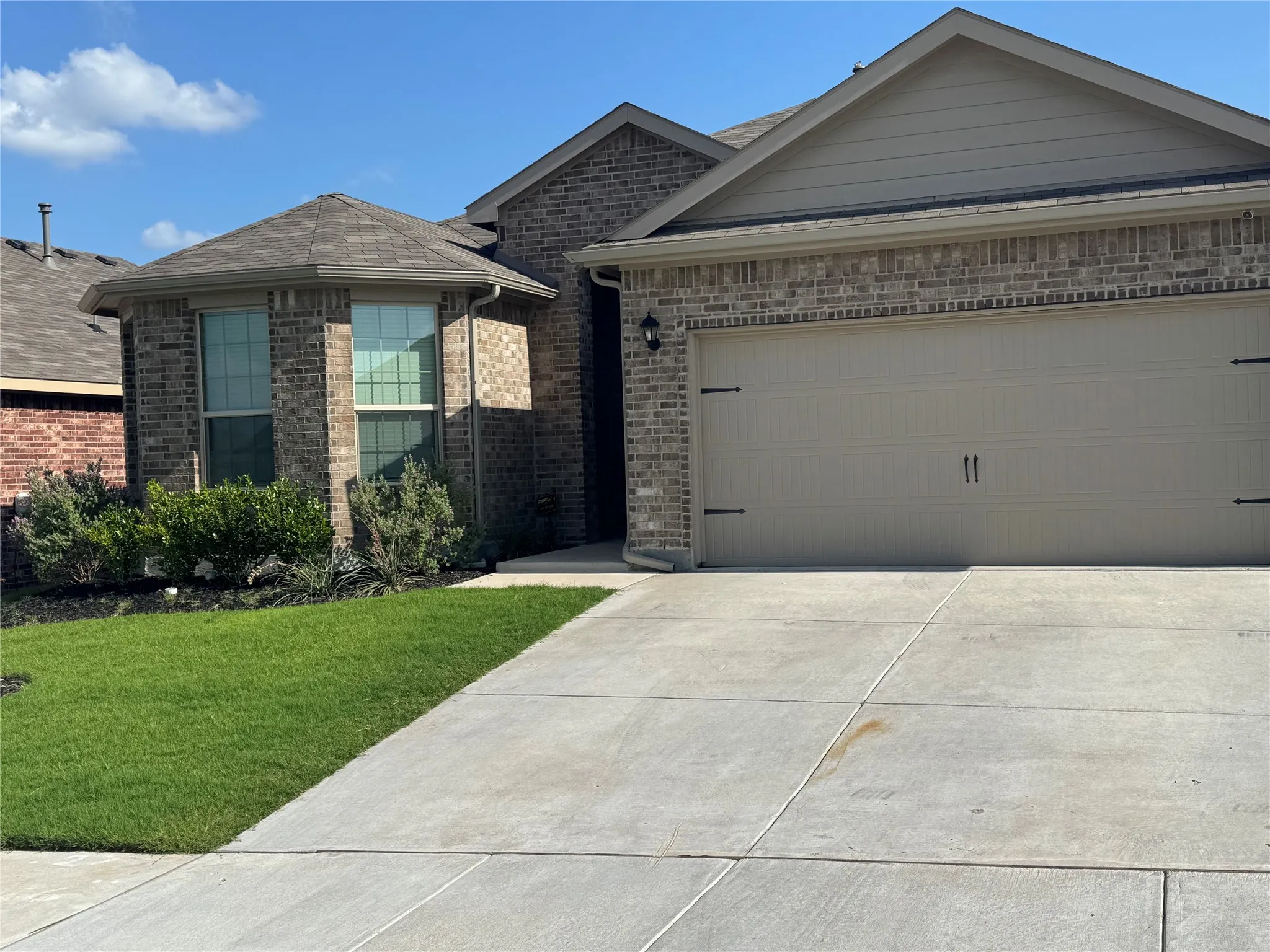 Single story home featuring concrete driveway, brick siding, a front yard, and a garage