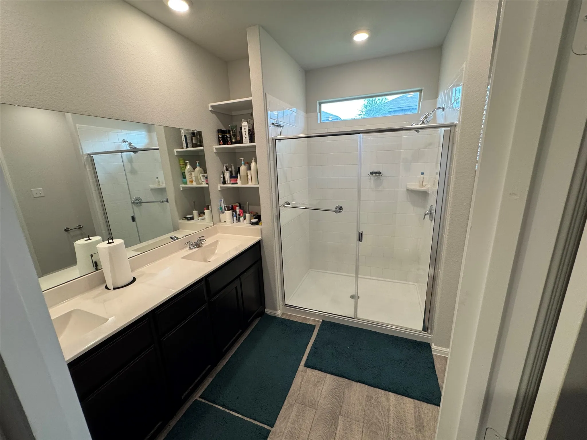 Full bathroom featuring a stall shower, double vanity, and wood finished floors