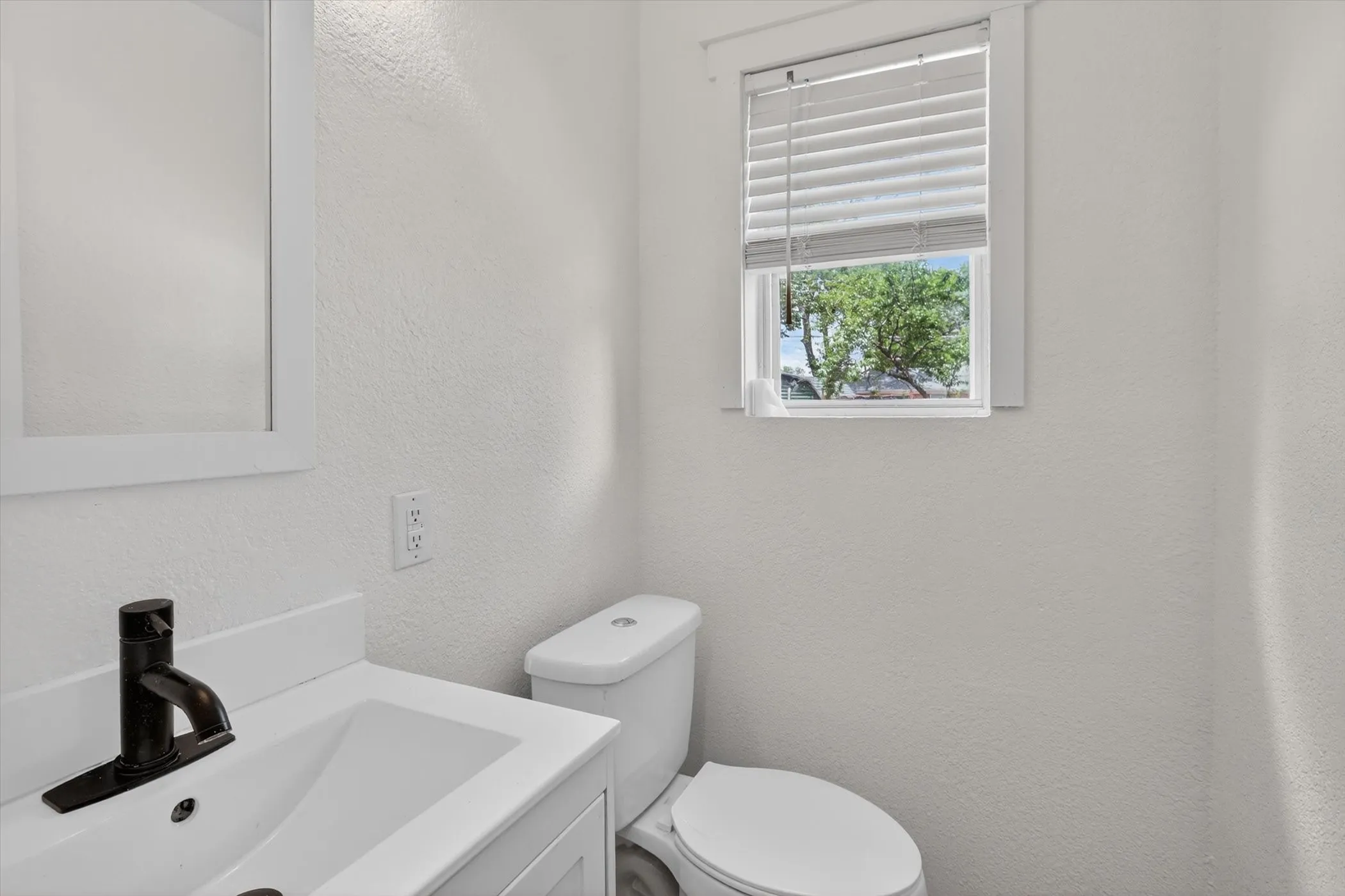 Bathroom featuring a vanity with an integrated sink, dark bronze-finish faucet, and a wall-mounted mirror