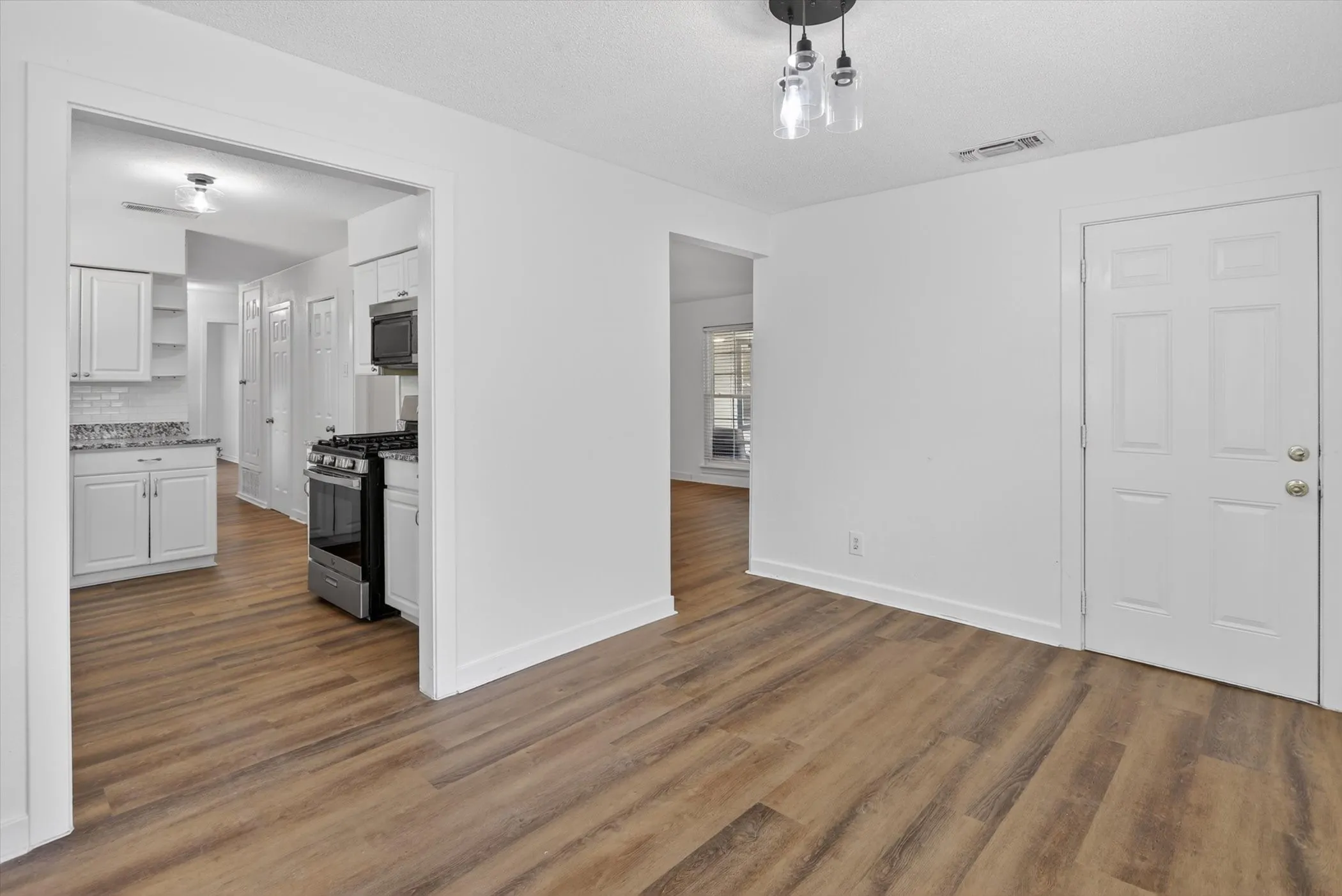 Spacious interior featuring wood-finish flooring, white paneled doors, and a modern ceiling light fixture