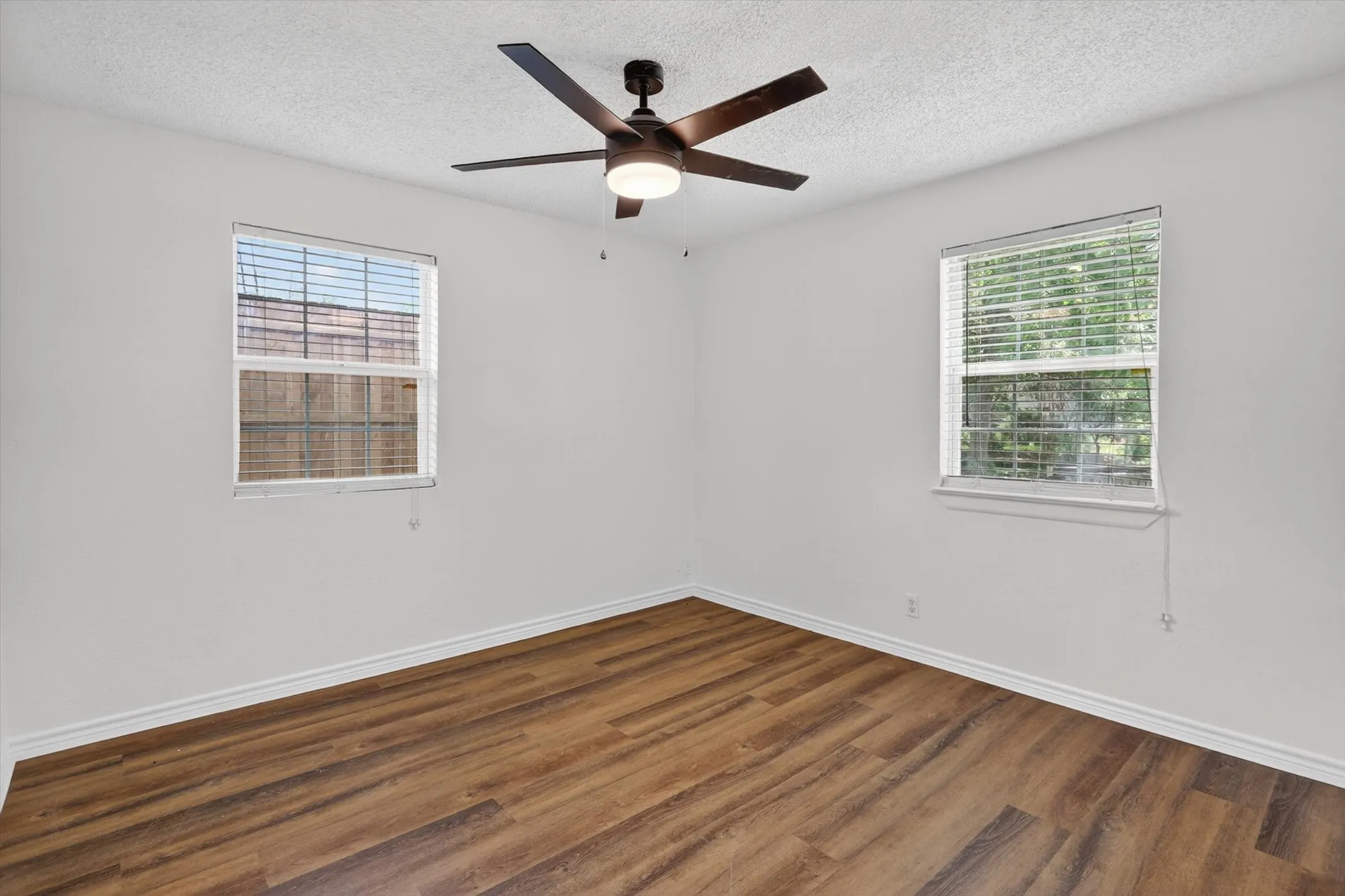 Room featuring wood-finish flooring, light-toned walls, and white baseboards