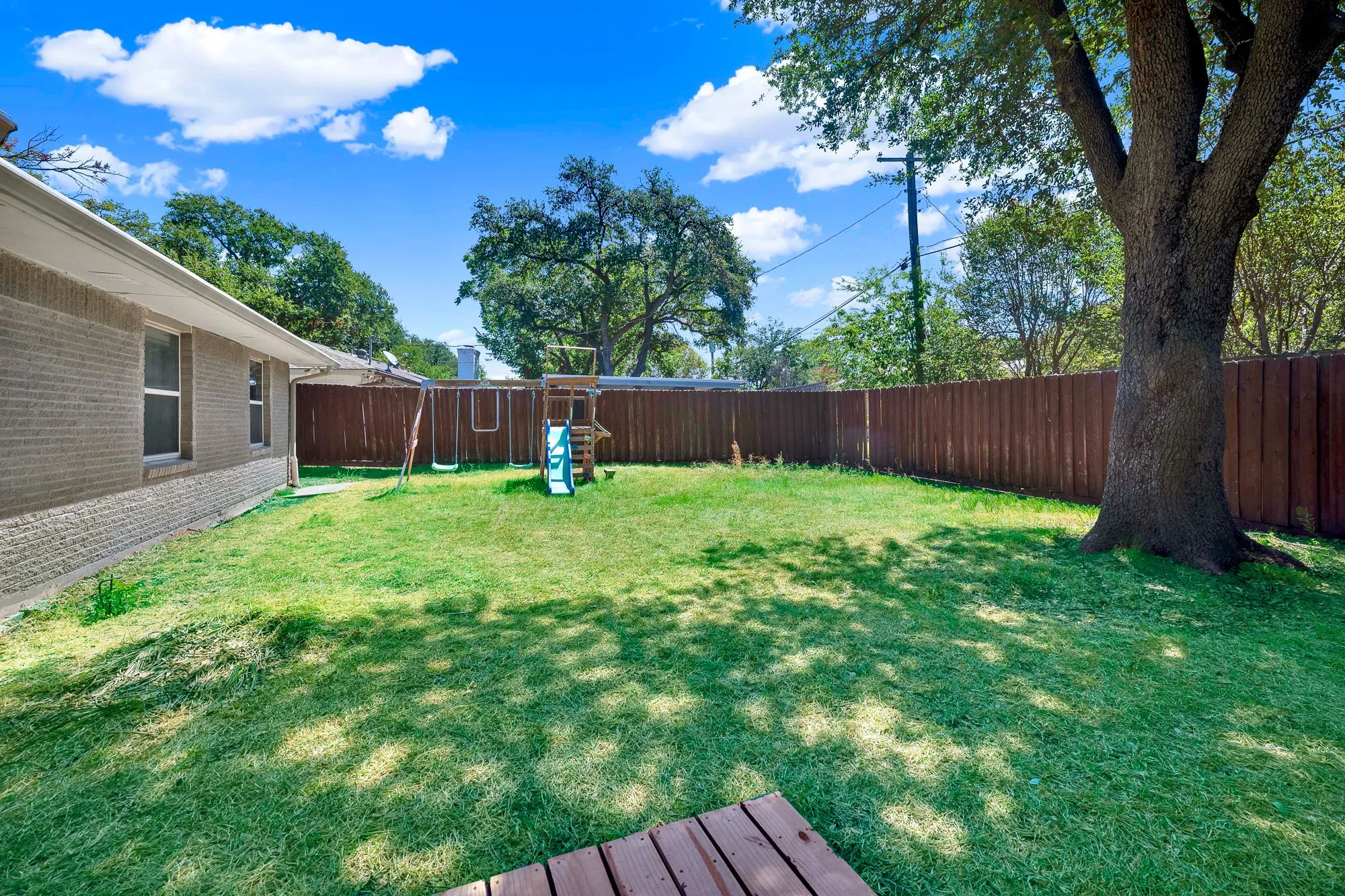Expansive green lawn, wood privacy fence, and mature shade tree