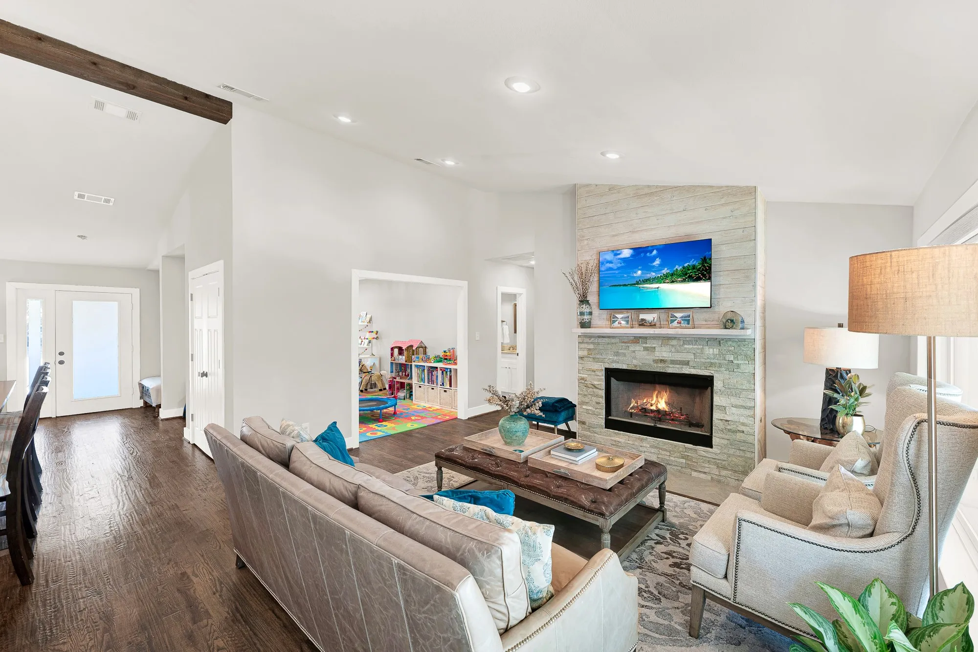 Living space featuring a stone-clad fireplace, wood-finish flooring, and recessed lighting