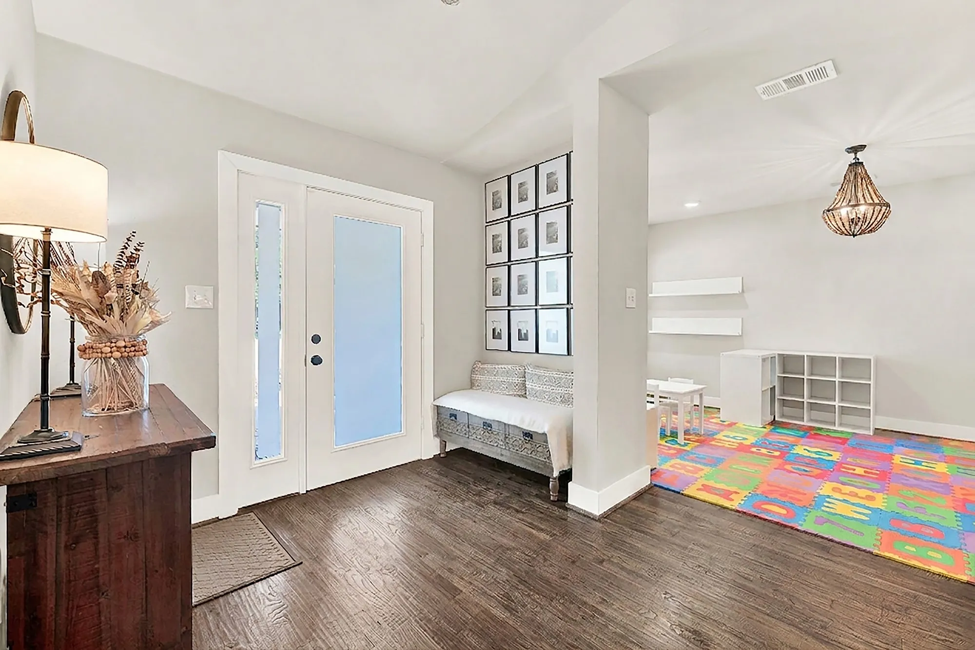 Hardwood-finish flooring throughout, frosted glass door with sidelight, recessed ceiling lighting, and a decorative wood chandelier