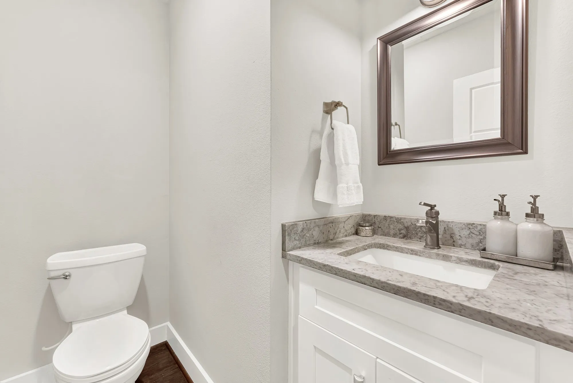 White vanity with integrated sink, patterned countertop, and framed mirror