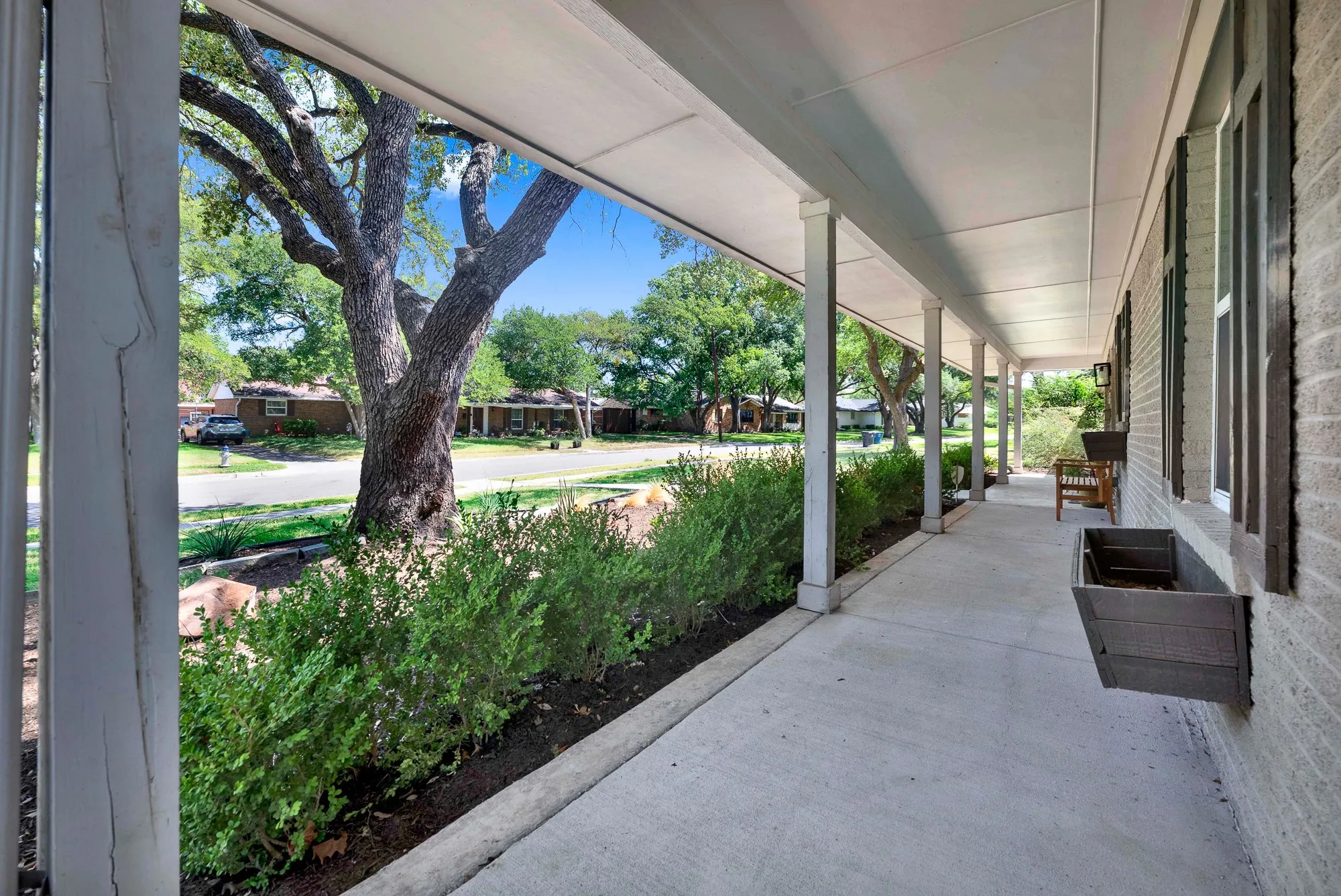 Expansive covered porch featuring a concrete surface and white support columns