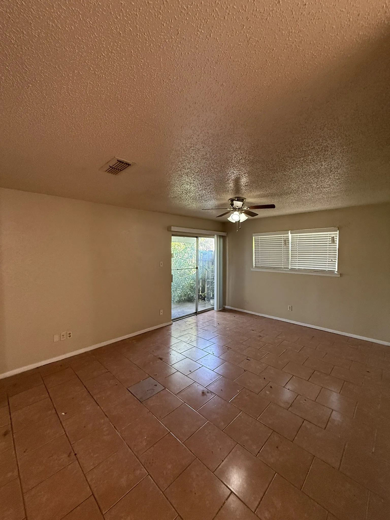 Tiled flooring, ceiling fan with integrated lighting, sliding glass door, and horizontal window blinds