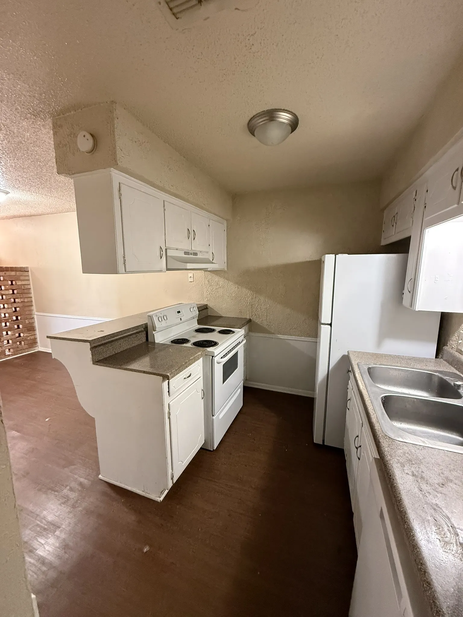 Wood-finish flooring, white cabinetry, integrated double basin sink, white range, and white refrigerator