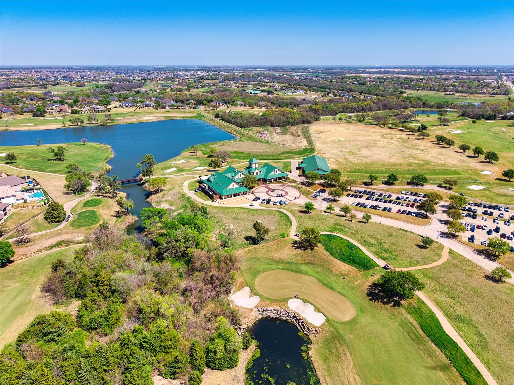 Expansive golf course setting featuring a clubhouse, water features, and manicured greens