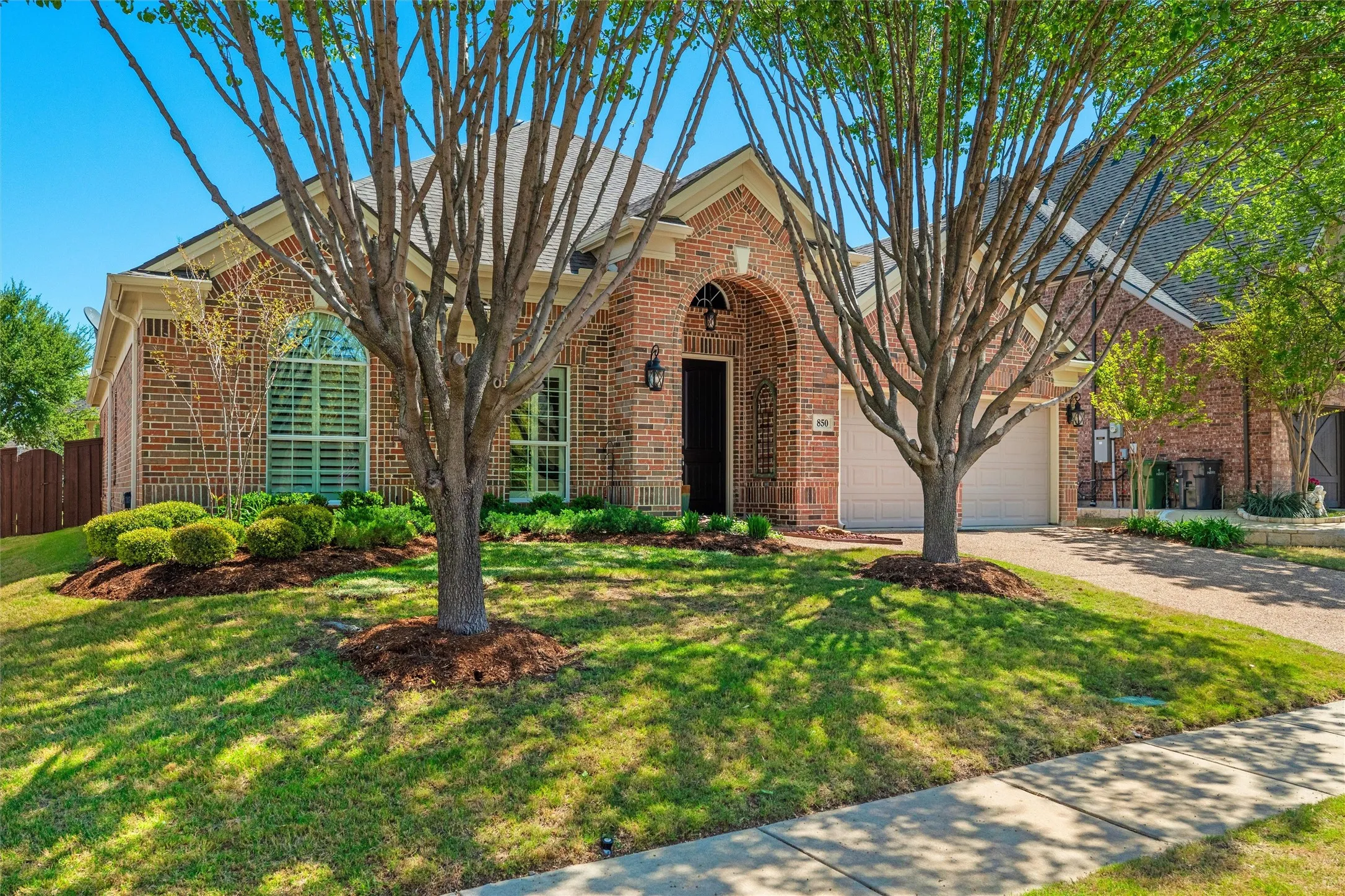 Brick exterior with arched entry, an attached two-car garage, and a concrete driveway