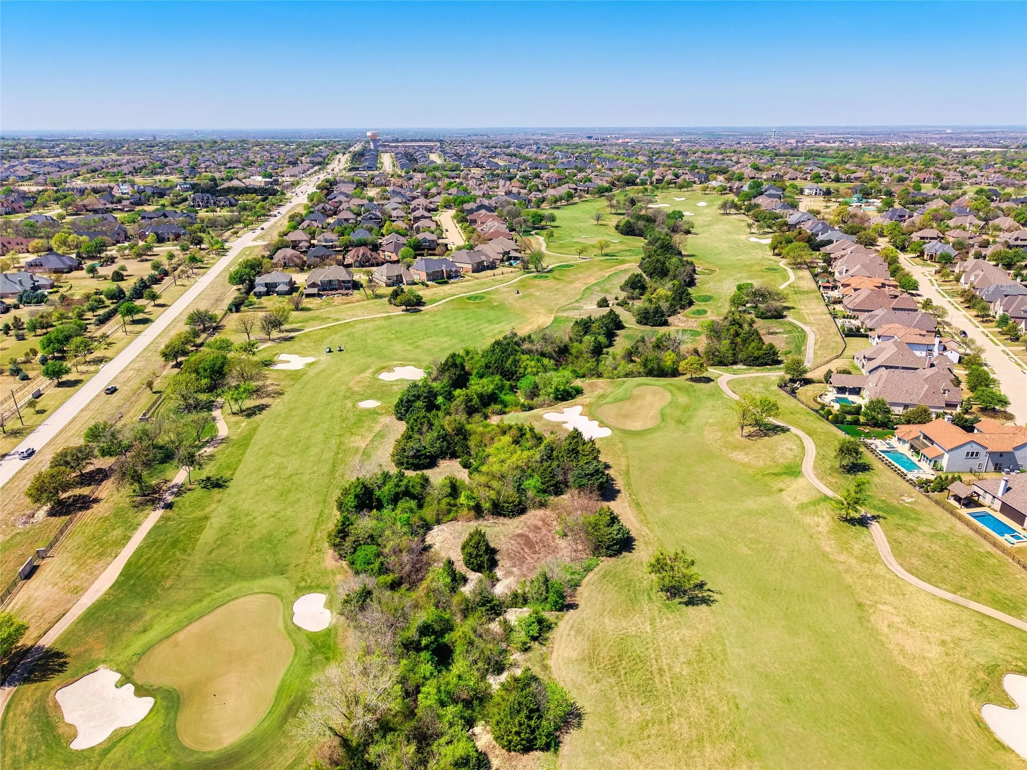 Expansive golf course setting featuring green fairways, sand traps, and mature trees