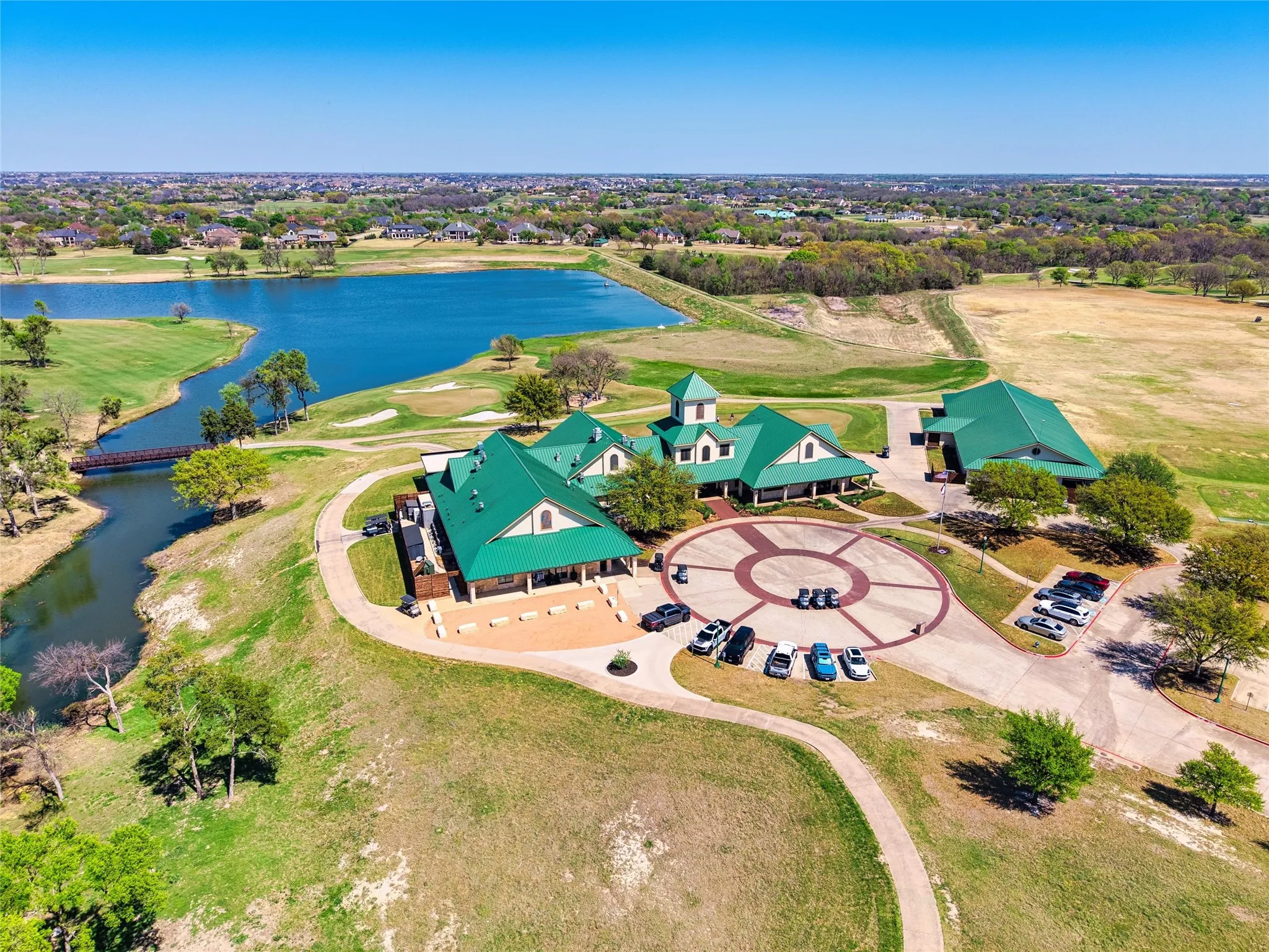 Expansive property featuring a multi-building complex with green roofs, a circular driveway with paver accents, and a large parking area