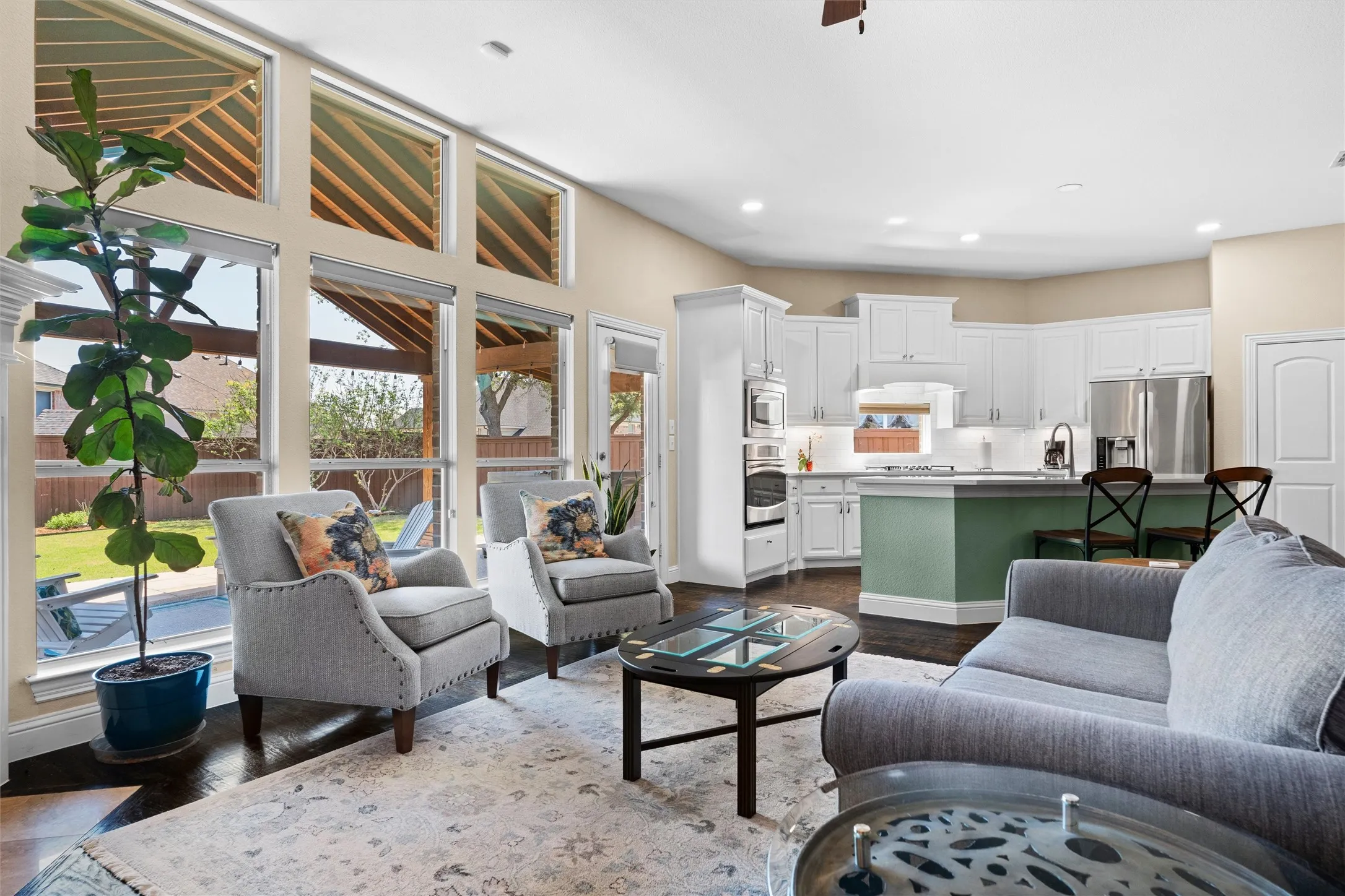 Expansive windows, high ceilings, dark wood-finish flooring, white cabinetry, and stainless steel appliances