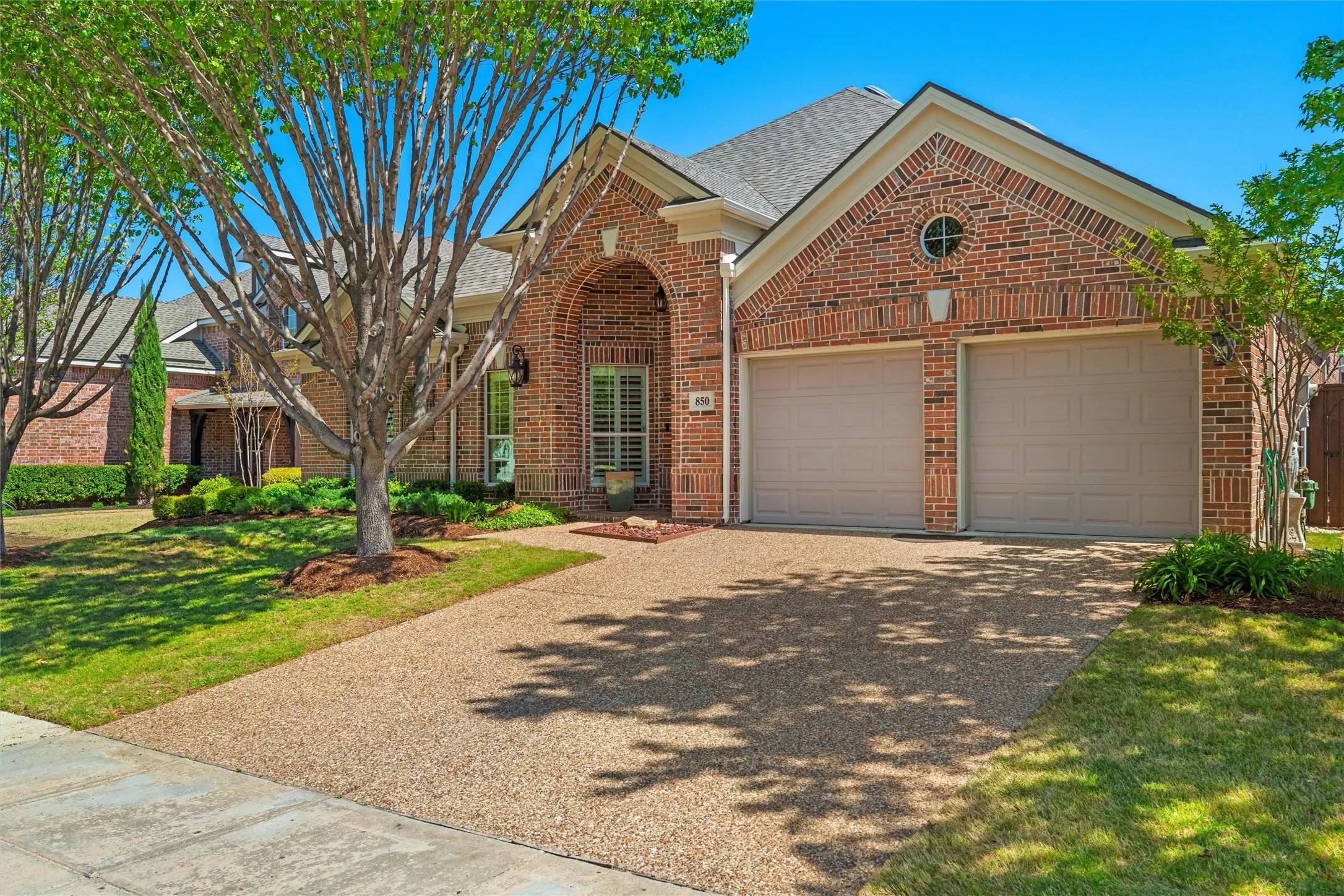 Brick exterior with an arched entry, two-car garage, and a round window detail
