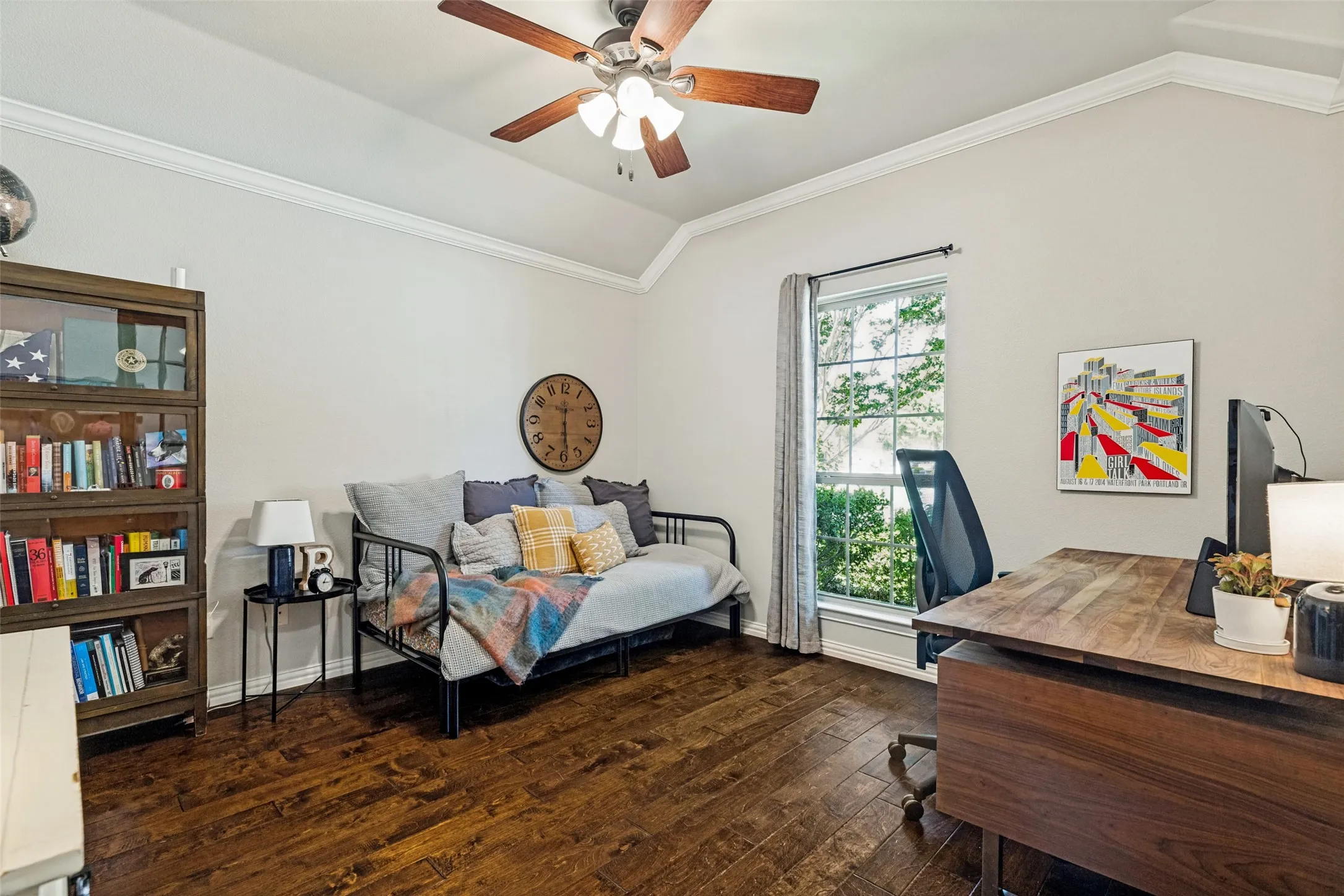 Vaulted ceiling with crown molding, wood-finish flooring, ceiling fan with light fixture, and a large window with ample natural light