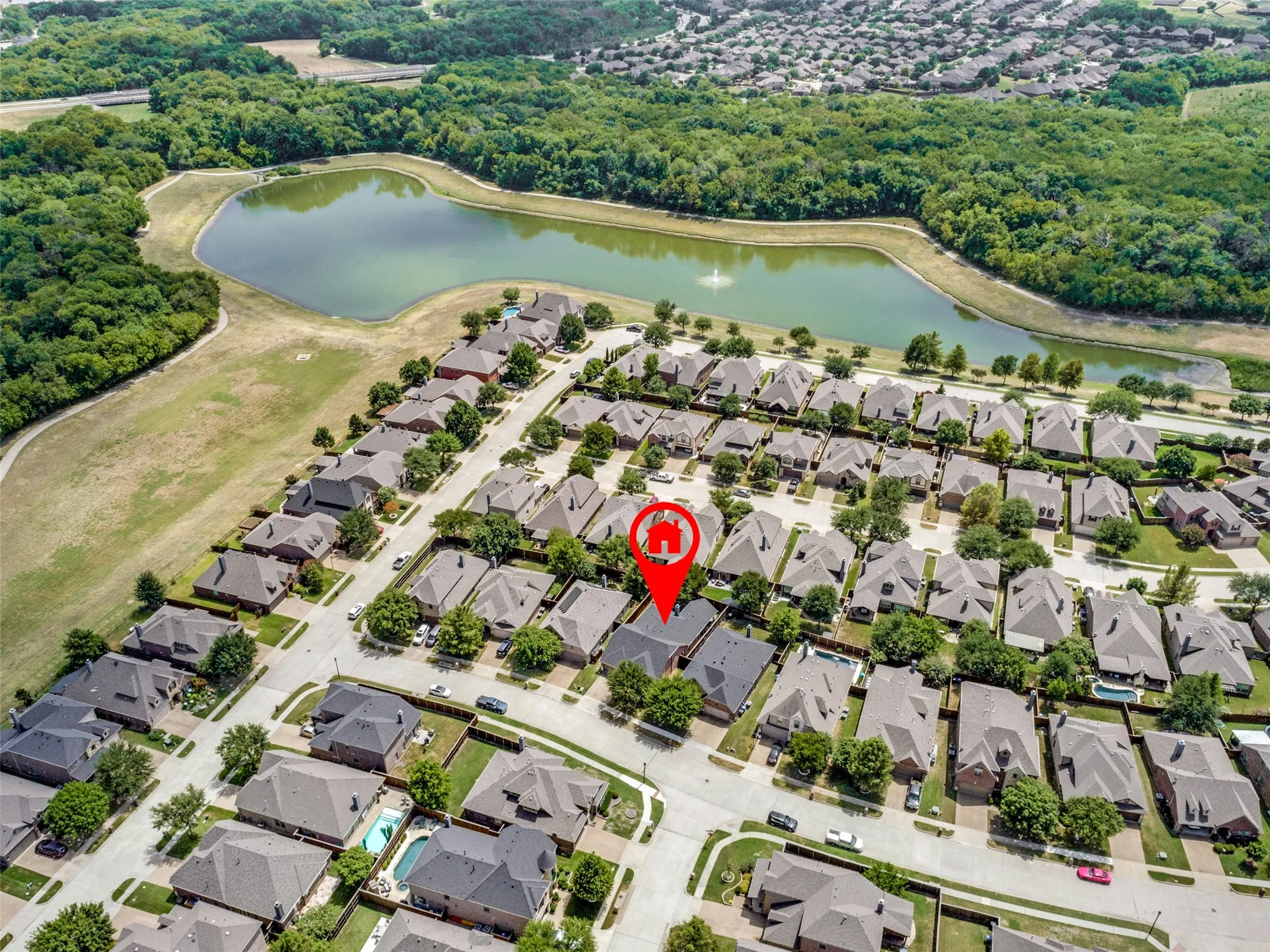 Aerial perspective of a residential neighborhood with a large pond and surrounding green space