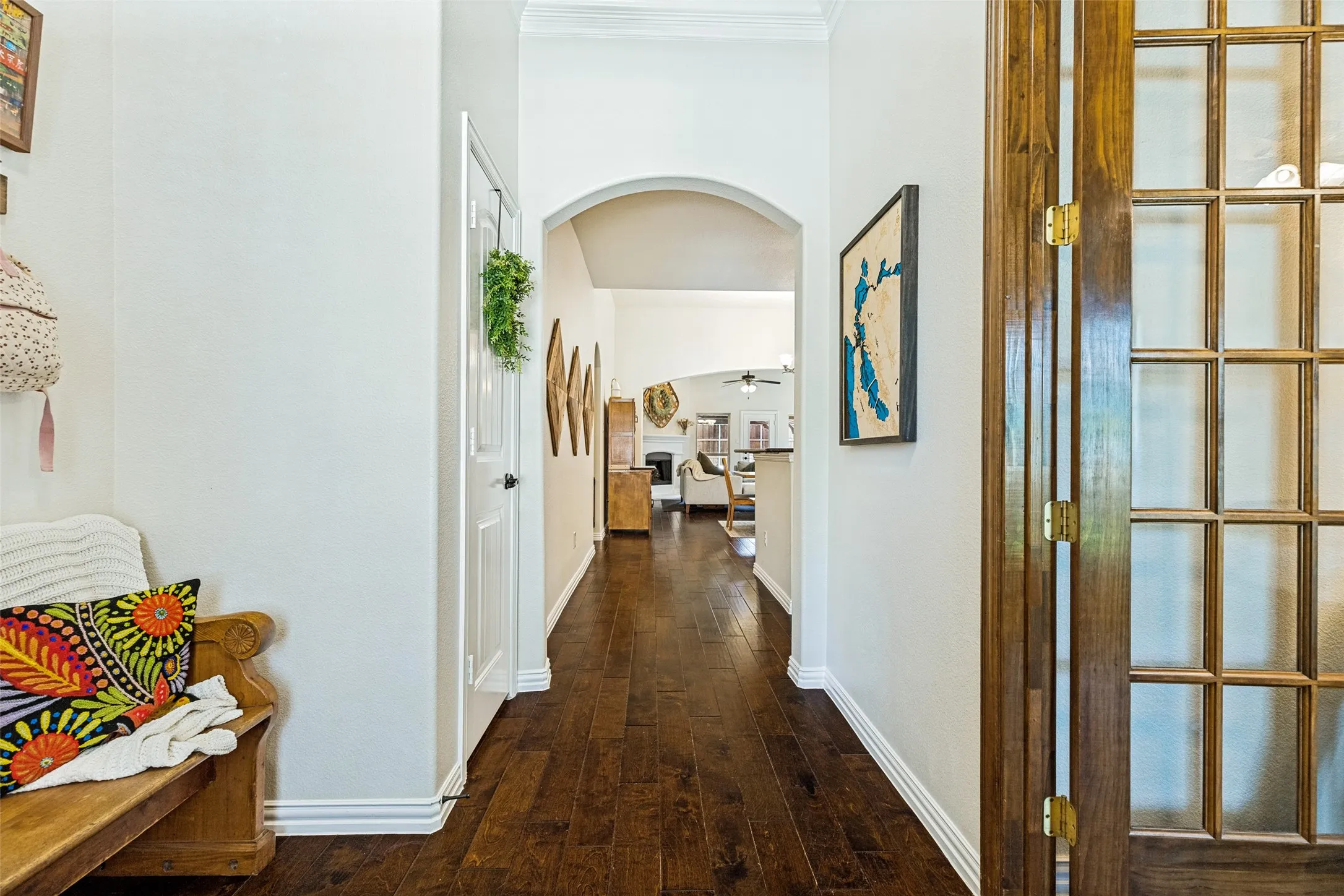 Vaulted ceiling with ceiling fan, wood-finish flooring, white fireplace, and multiple windows