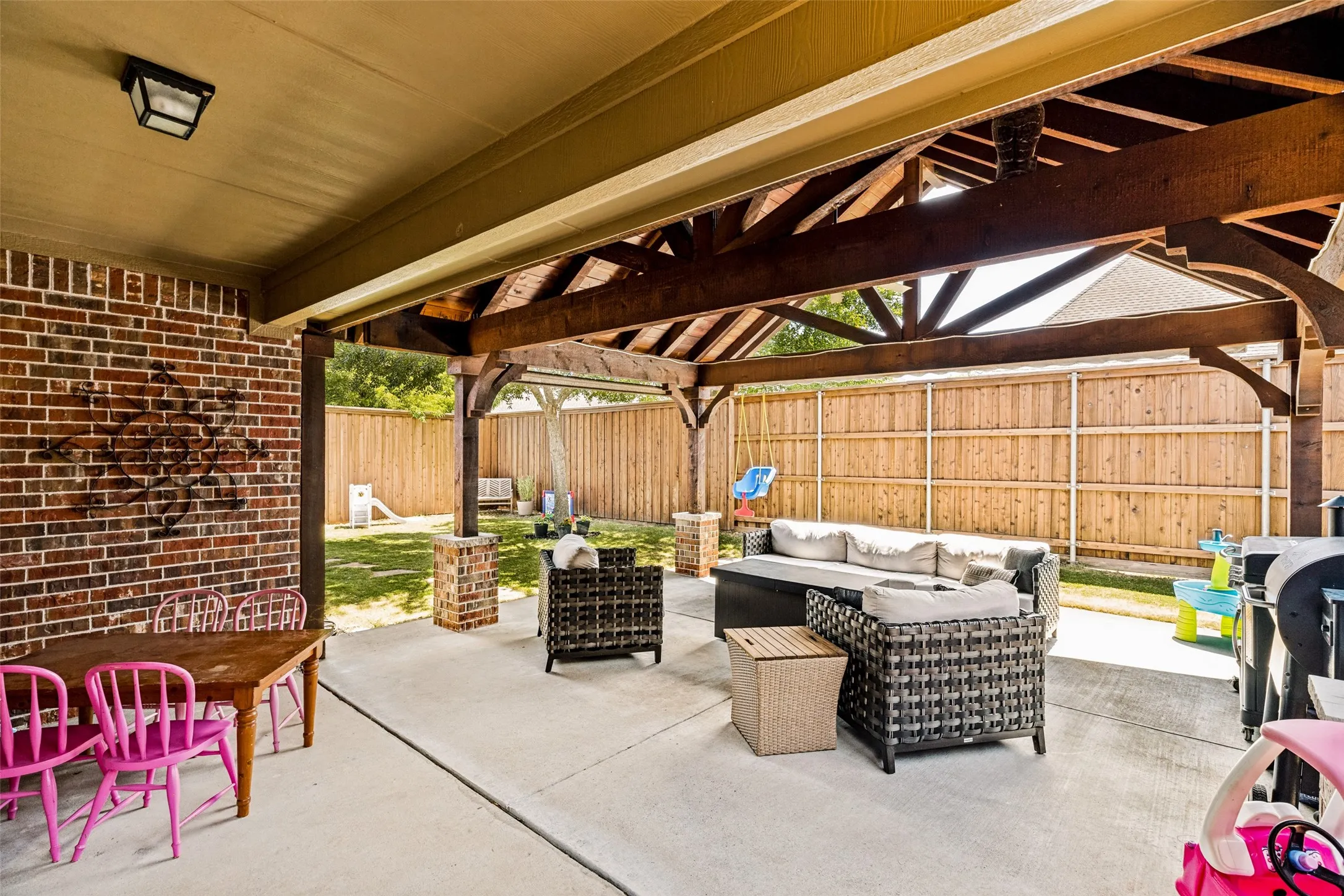Expansive concrete patio with a vaulted wood-beam pergola