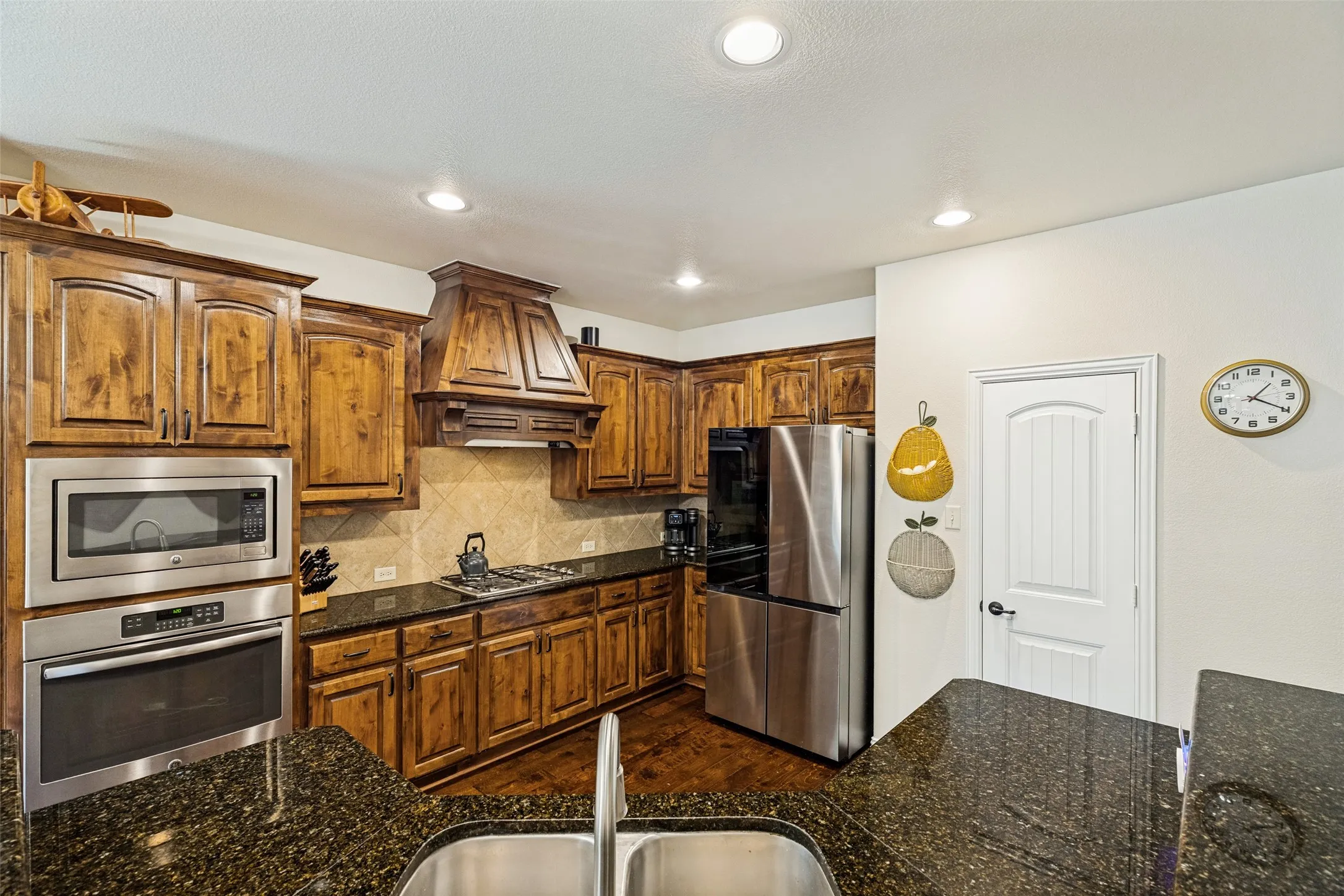 Kitchen featuring wood cabinetry, stainless steel appliances, dark stone countertops, and a built-in oven and microwave