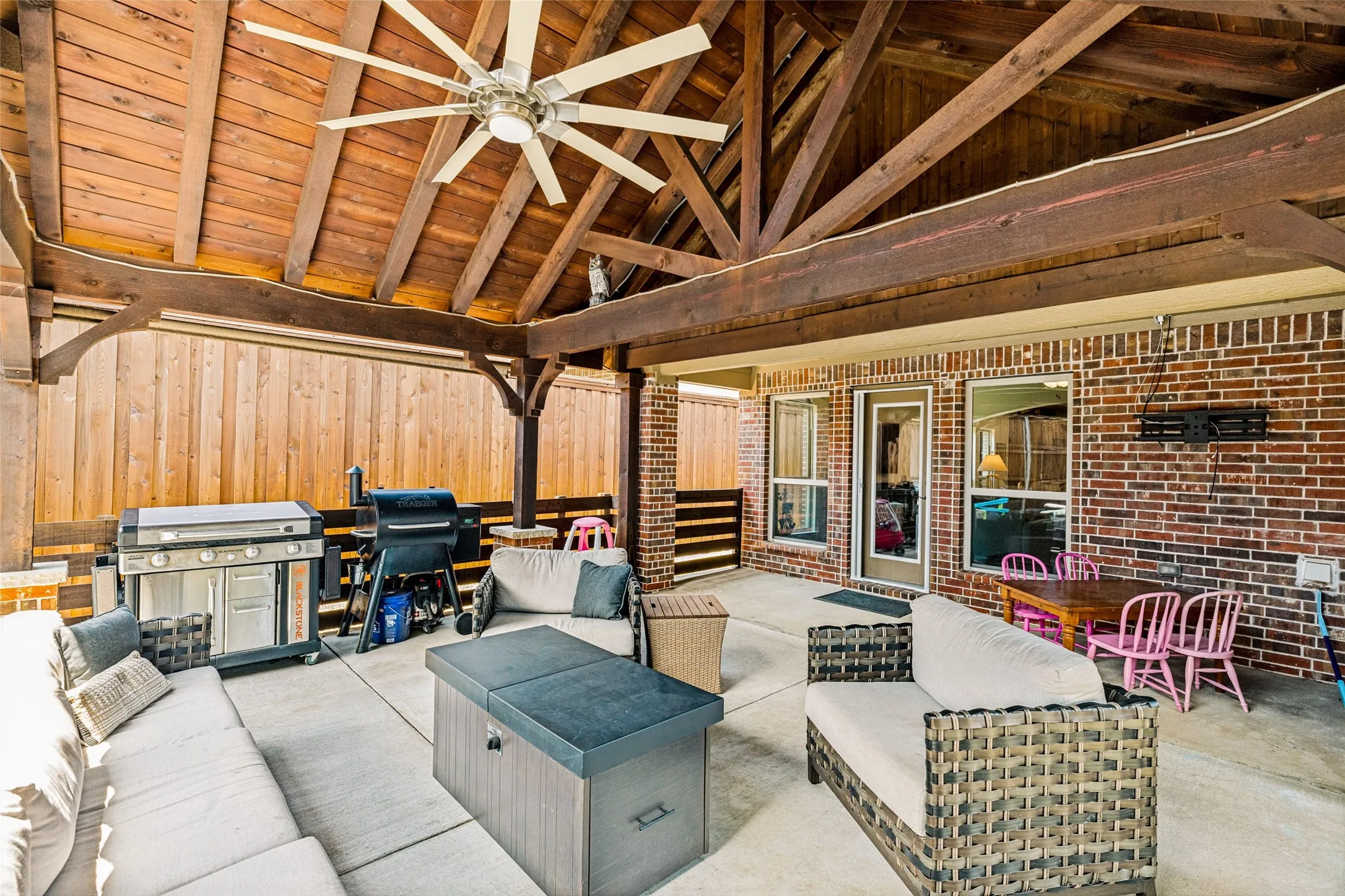 Covered patio featuring a wood-plank ceiling, exposed wood beams, and a ceiling fan