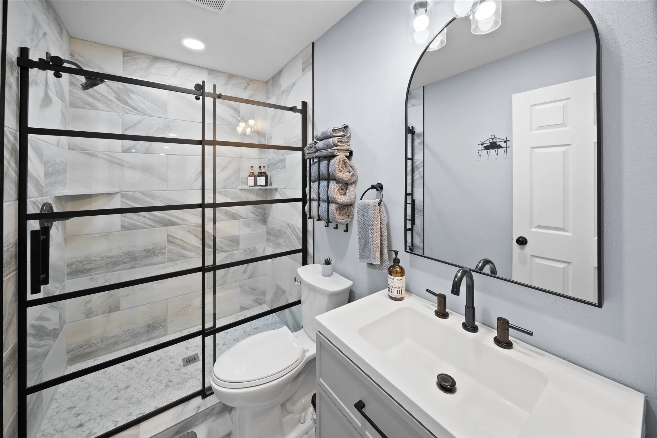 Walk-in shower with a black-framed glass enclosure, tiled walls, and a recessed shelf