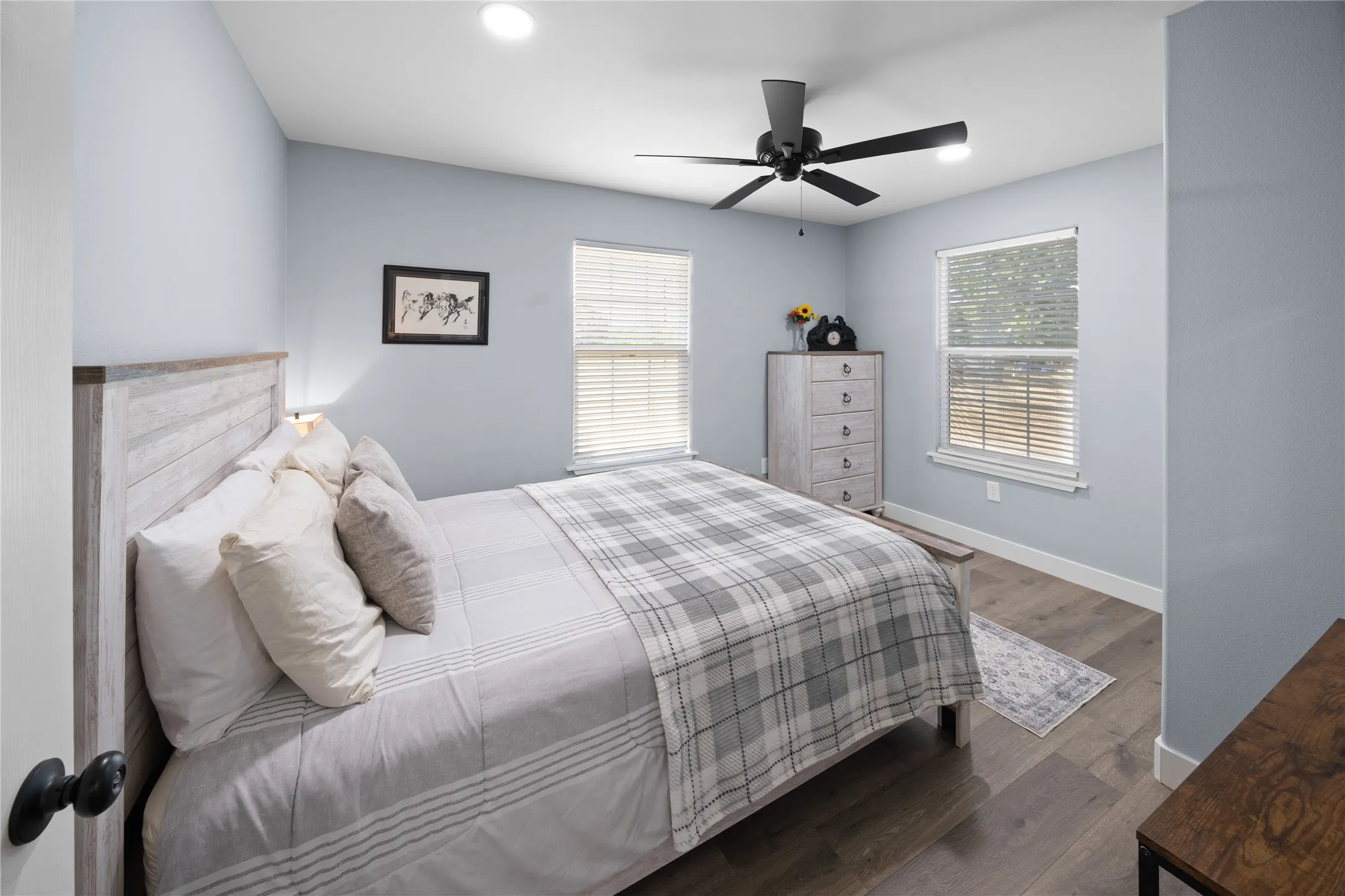 Recessed lighting, wood-finish flooring, two windows with blinds, and a ceiling fan with integrated lighting