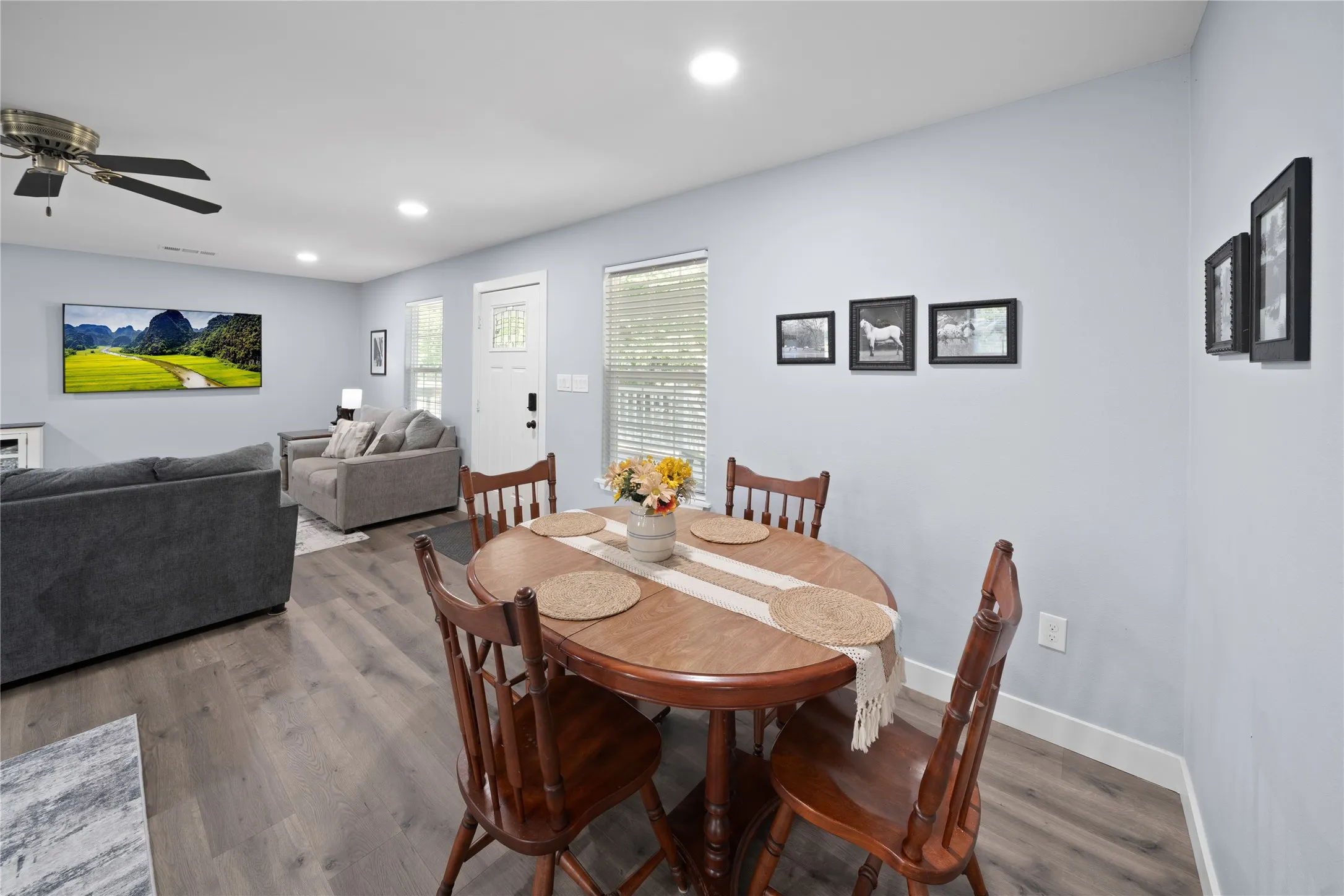 Open-concept living space with wood-finish flooring, ceiling fan, recessed lighting, and white trim