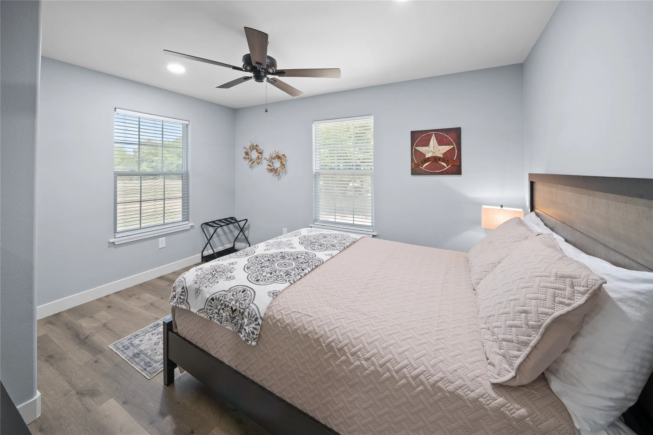 Recessed ceiling lighting, wood-finish flooring, two windows with blinds, and a ceiling fan
