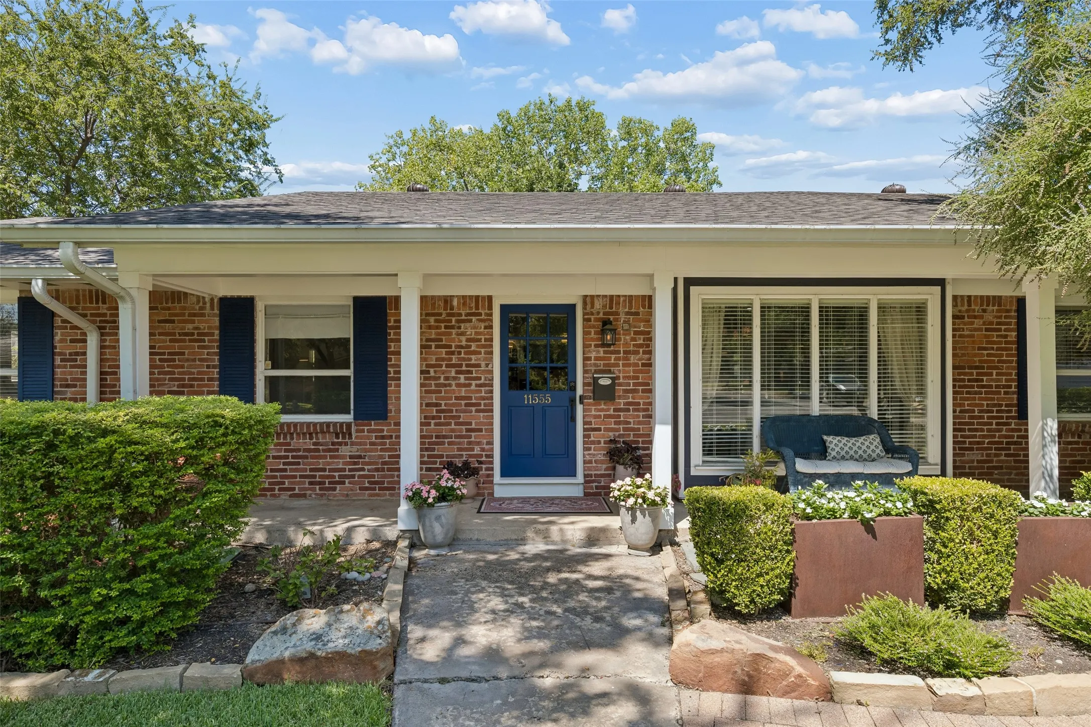 Covered front porch with seating and landscaped floor beds.