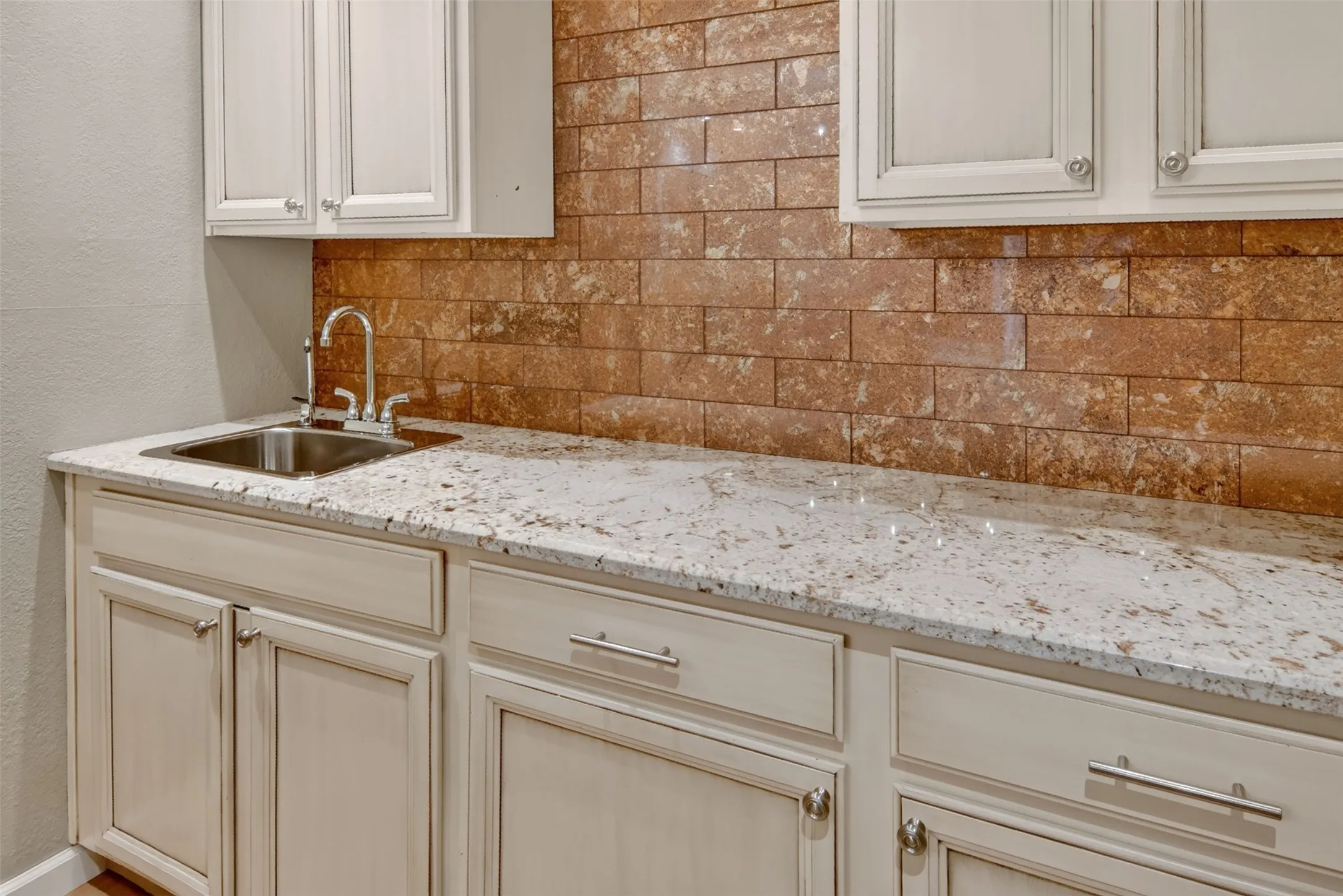 Up close view of the wet bar with sink, granite countertops, And beautiful brick backsplash
