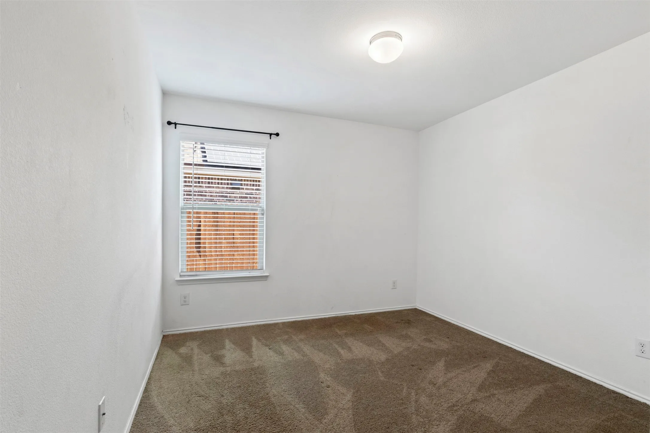 Recessed window with blinds and a dark-finish curtain rod
