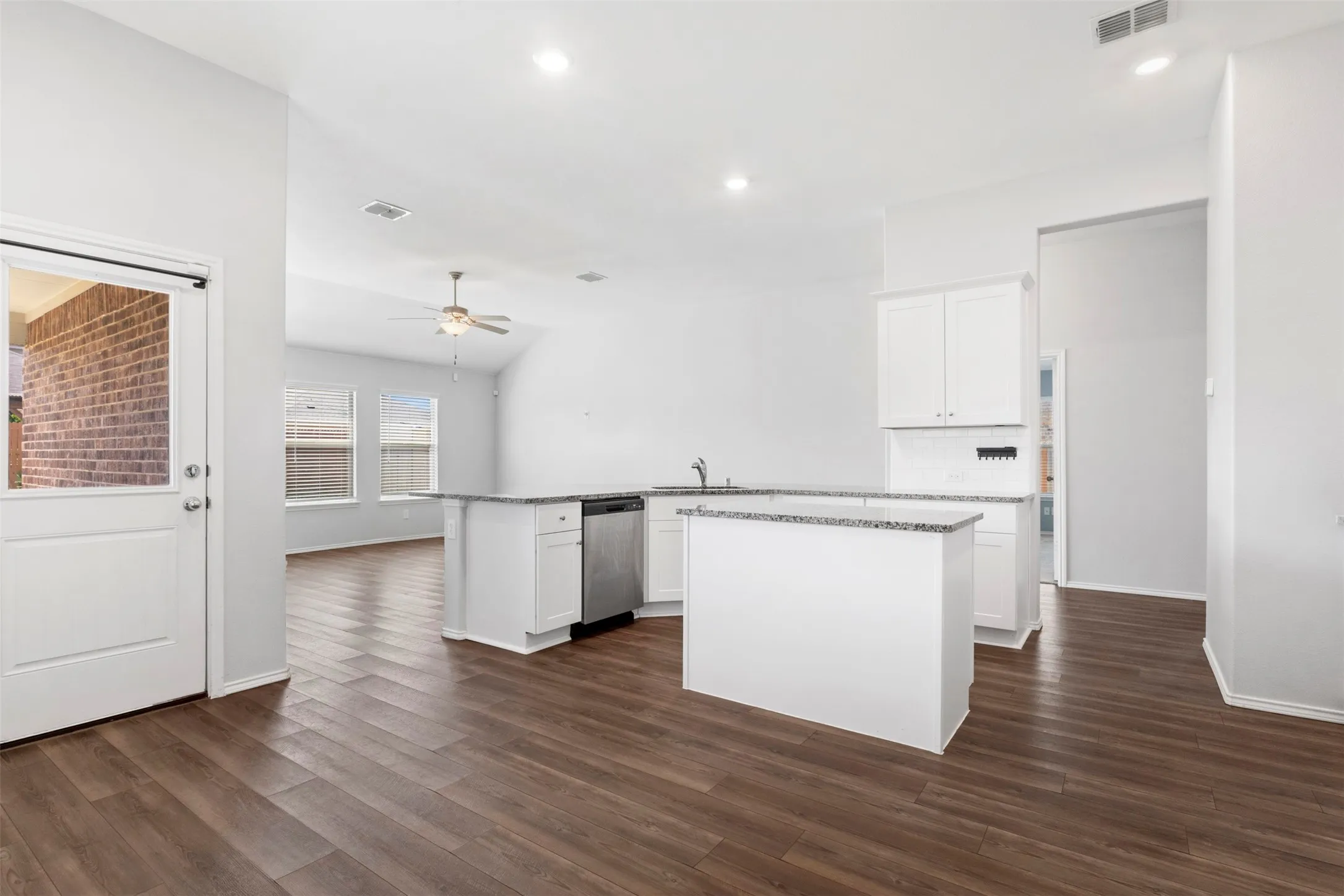 Kitchen featuring white cabinetry, stainless steel dishwasher, and a two-tier peninsula with a light-toned countertop