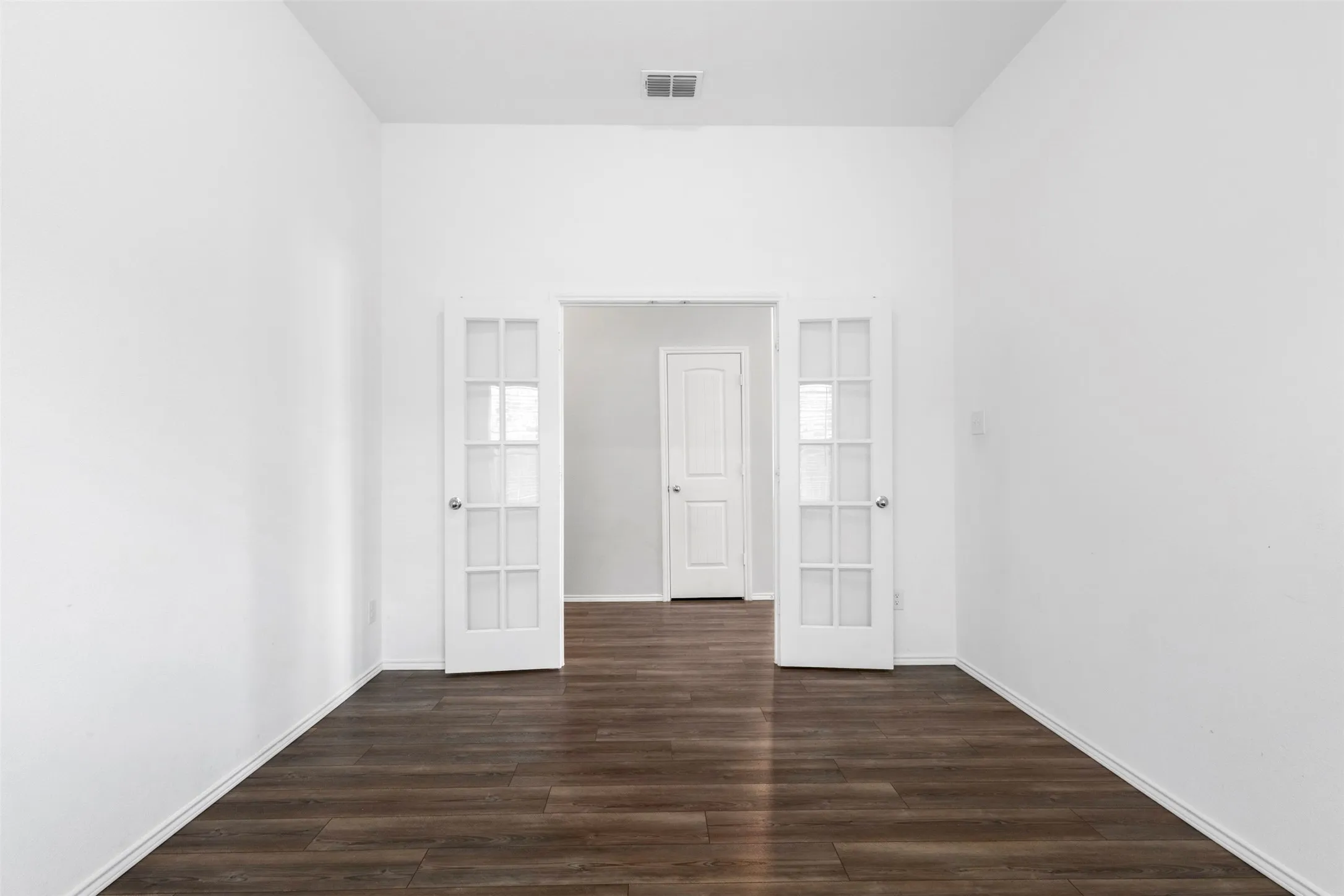 Interior room featuring wood-finish flooring, white painted walls, and double French doors