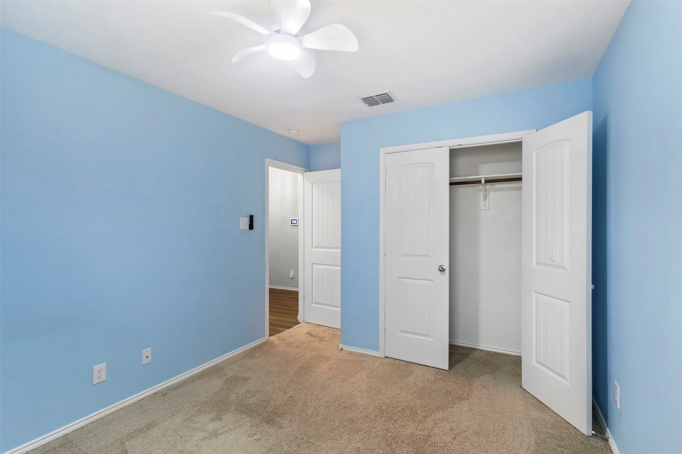 Carpeted room with a ceiling fan, light blue painted walls, and white trim