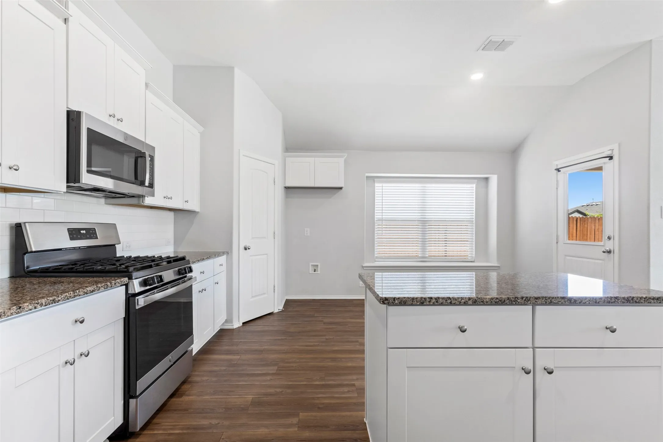 Kitchen featuring white cabinetry, stainless steel appliances, granite countertops, wood-finish flooring, and recessed lighting