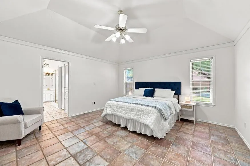Vaulted ceiling with a ceiling fan, white window blinds, and tile flooring