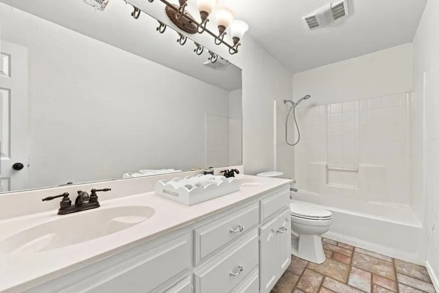 Bright, spa-inspired bathroom featuring a dual-sink vanity with ample storage, quartz countertop, and brushed nickel hardware