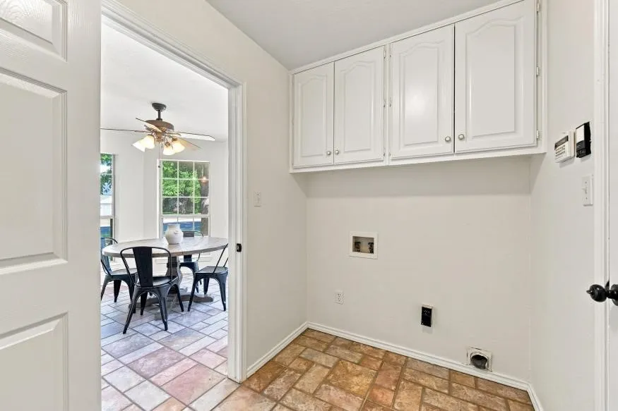 White paneled upper cabinetry, tile flooring, and utility connections