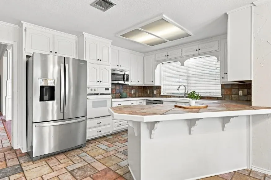 White cabinetry and a stainless steel refrigerator
