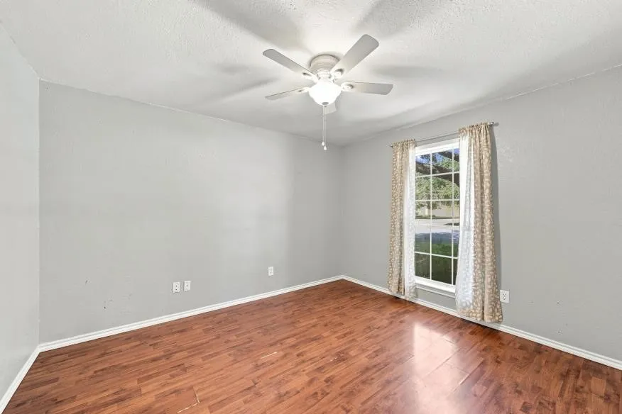 Wood-finish flooring with a ceiling fan and overhead lighting