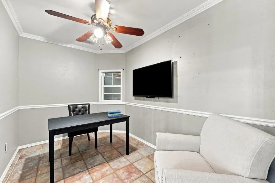 Room featuring a ceiling fan with light fixture, window with grid panes, and a mounted television