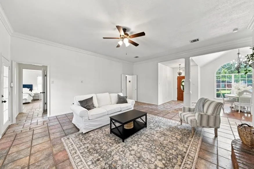 Tile flooring throughout with crown molding and a ceiling fan