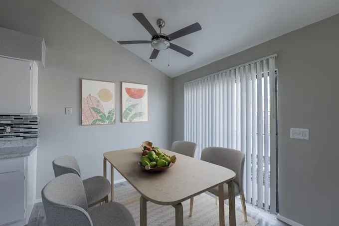 Vaulted ceiling with a ceiling fan, sliding glass door with vertical blinds, tile backsplash, and a countertop with an integrated sink
