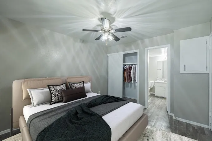Wood-finish flooring, ceiling fan with integrated lighting, sliding closet doors, and painted interior walls