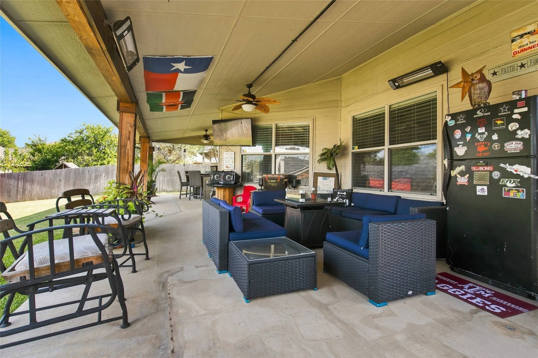 Covered patio featuring concrete flooring, ceiling fan, and woven rattan seating with blue cushions