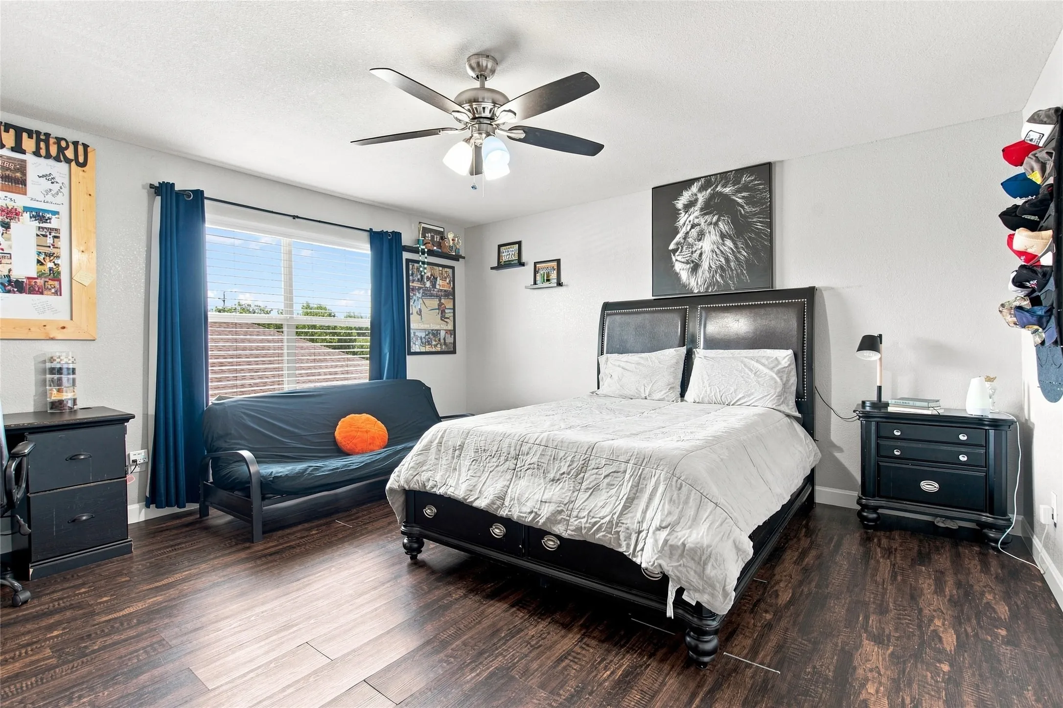 Wide window, dark wood-finish flooring, ceiling fan with light, light-colored walls